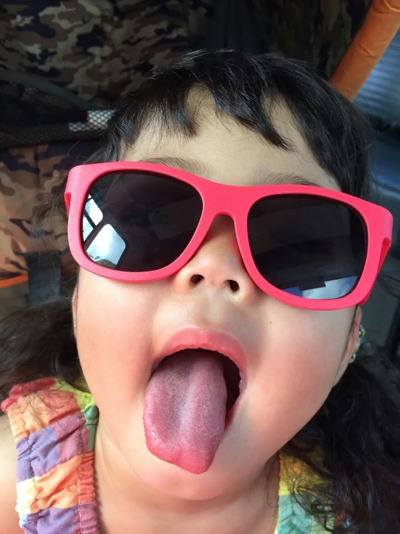 Kind mit rosa Sonnenbrille, das die Zunge herausstreckt