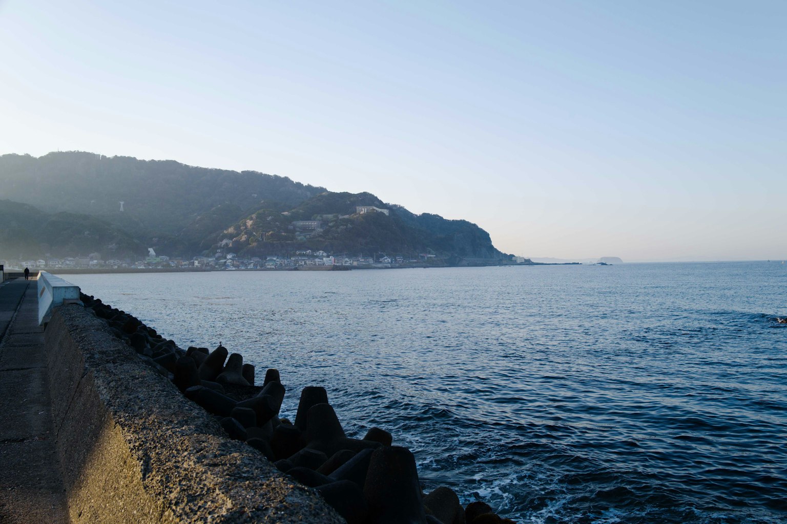 Pemandangan pantai yang tenang dengan gunung dan laut saat fajar