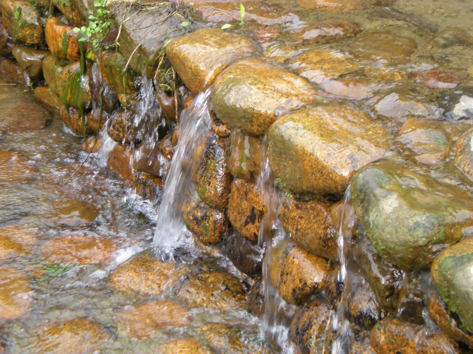 Flowing water over a stone wall with a natural setting