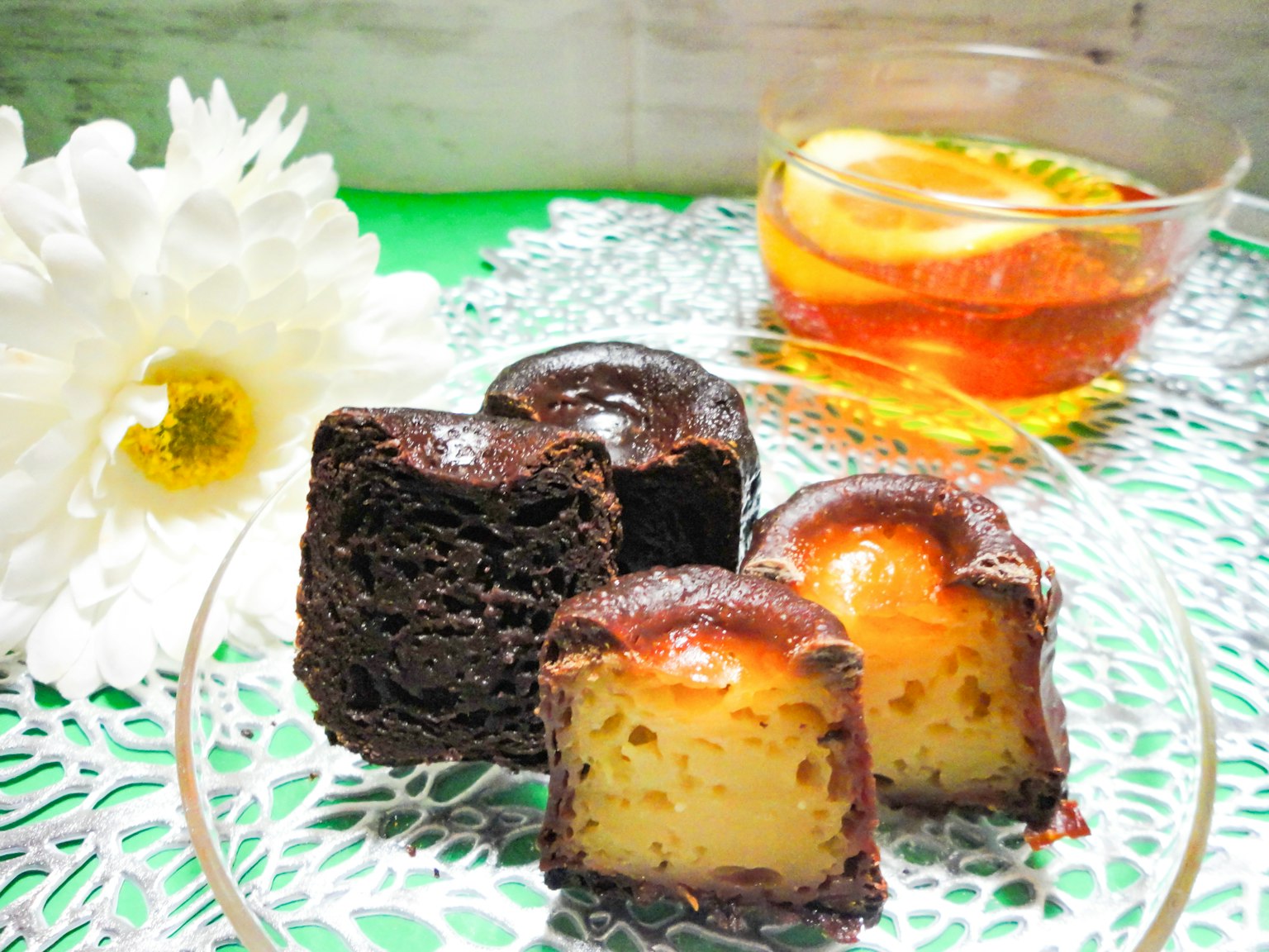 A plate of cannelés accompanied by a flower and a cup of tea