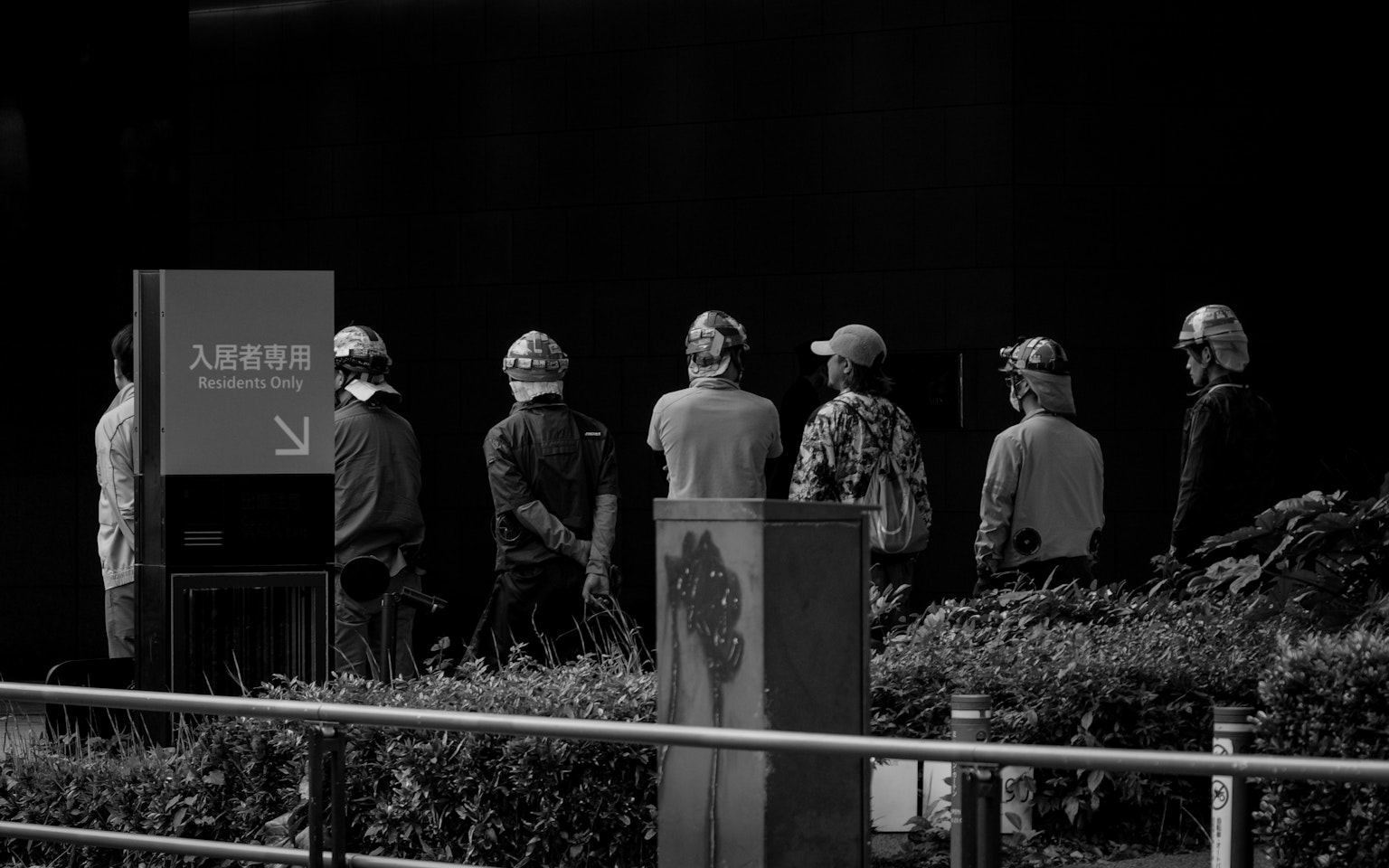 검은 배경 앞에 서 있는 헬멧을 쓴 사람들의 줄