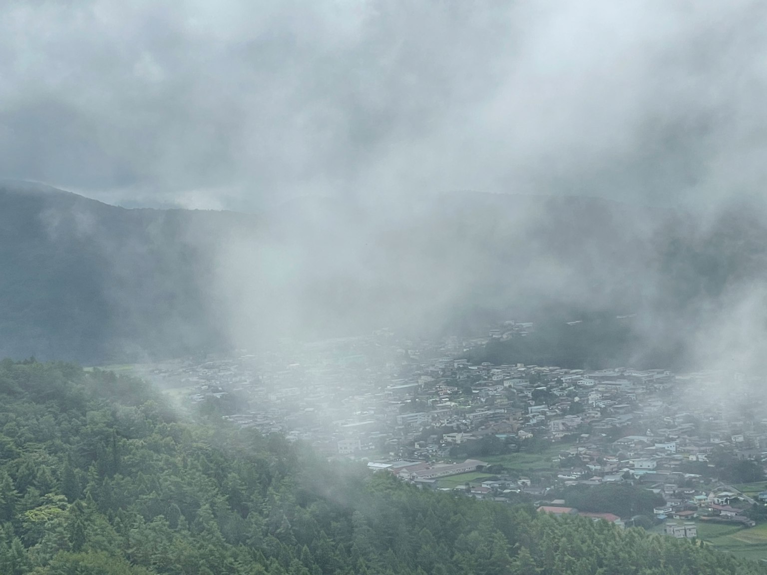 Pemandangan berkabut dengan pegunungan dan sebuah desa kecil