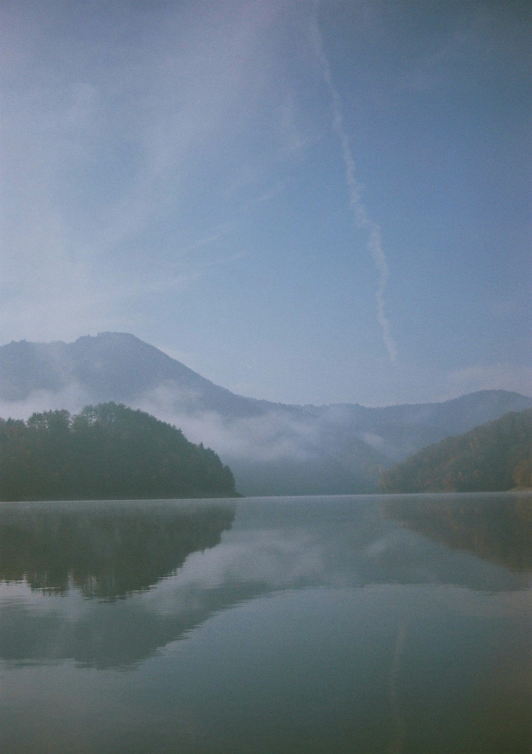 霧のかかった湖と山並みの静かな風景