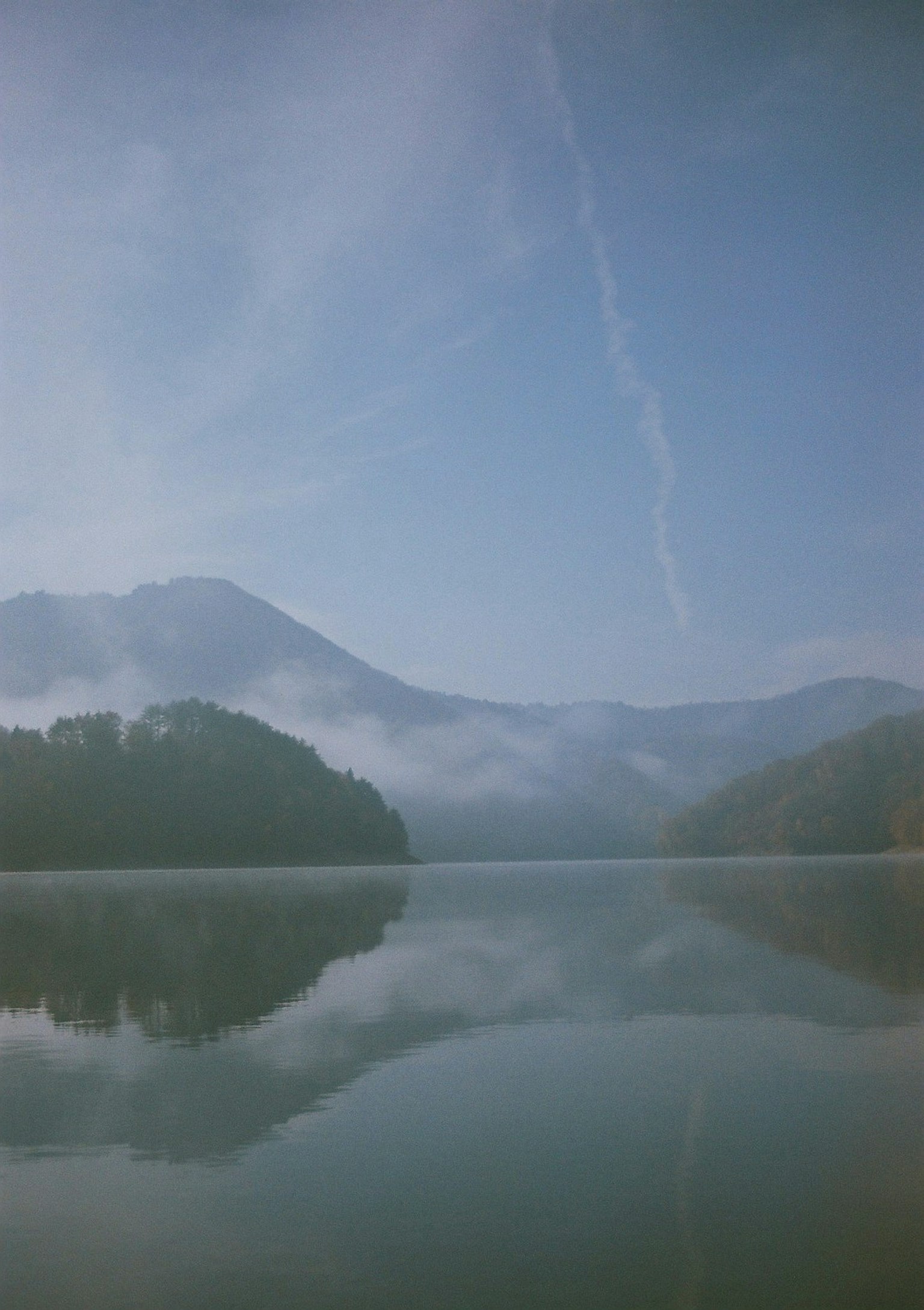 Serene landscape of misty mountains and calm lake