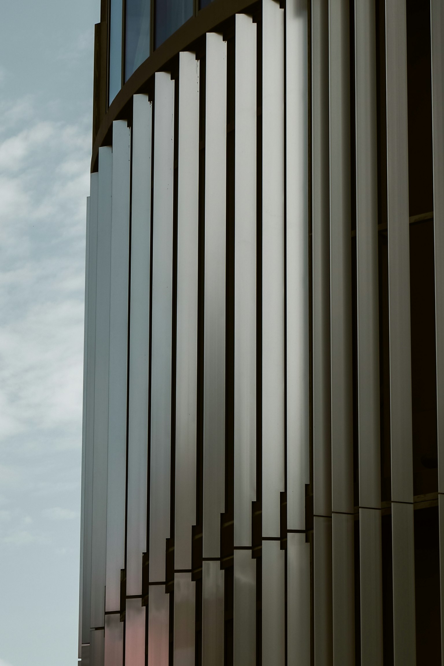現代建築金屬外立面的特寫，具有光澤的垂直條紋