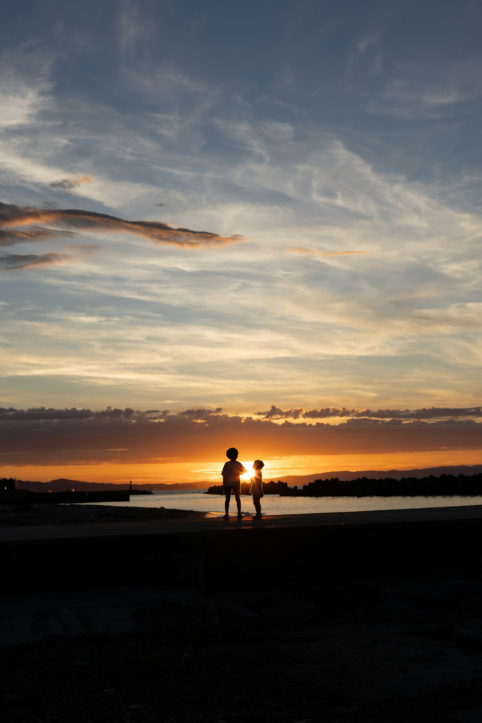 Silhouette de deux personnes se tenant devant un coucher de soleil