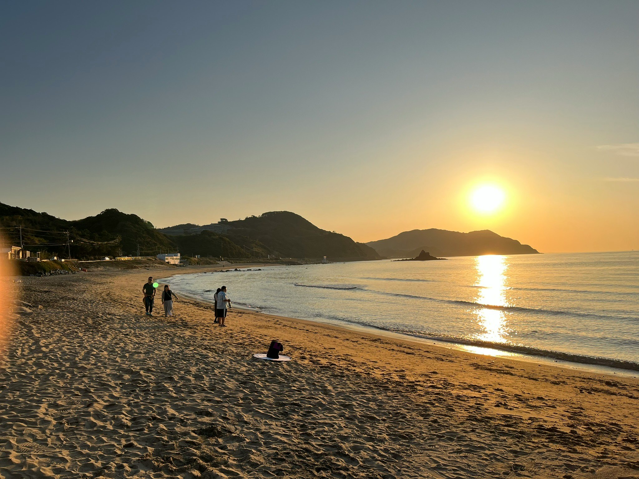夕日に照らされた砂浜を歩く人々のある海岸の風景