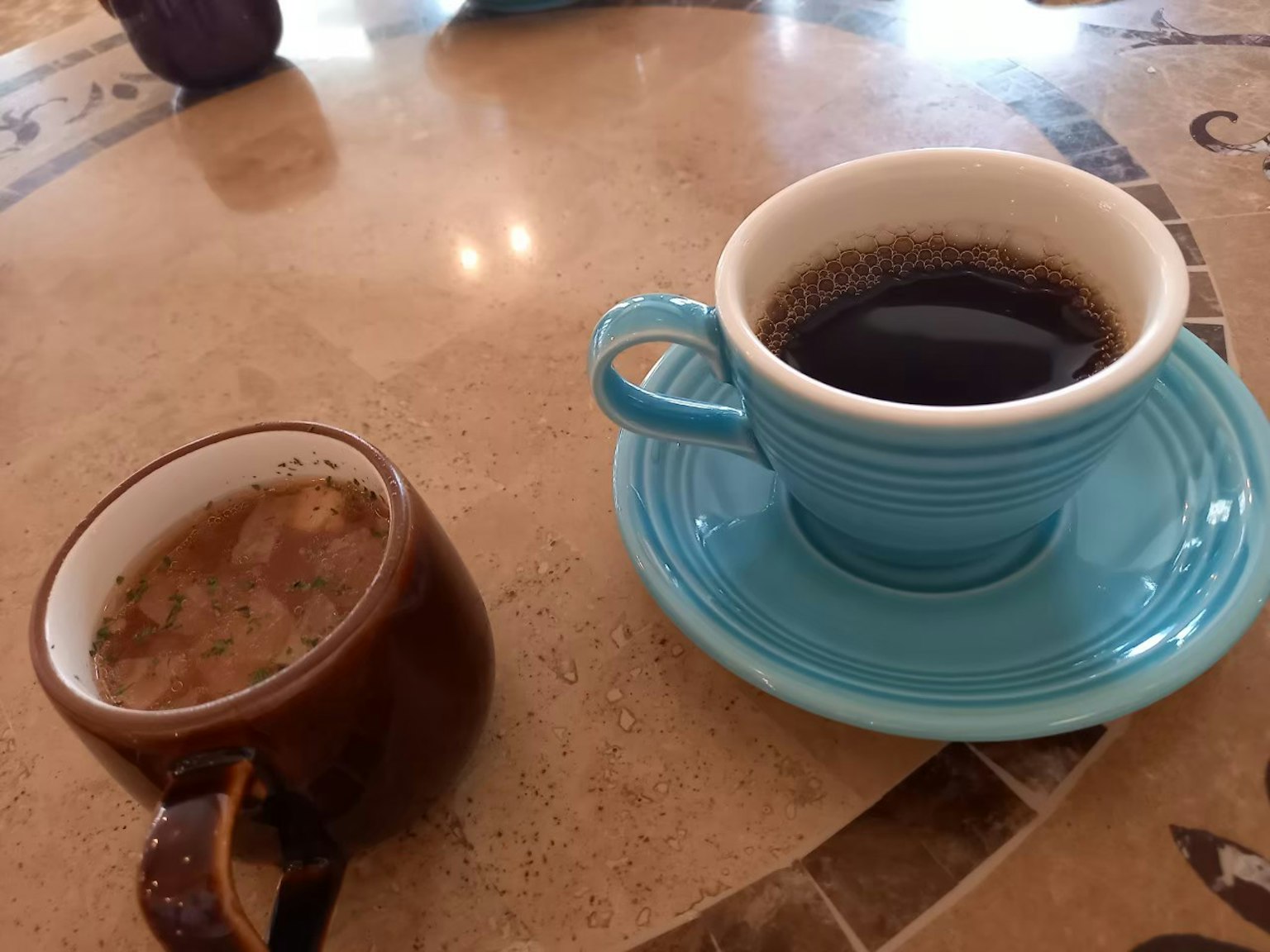 ถ้วยกาแฟสีน้ำเงินและถ้วยสีน้ำตาลบนโต๊ะ