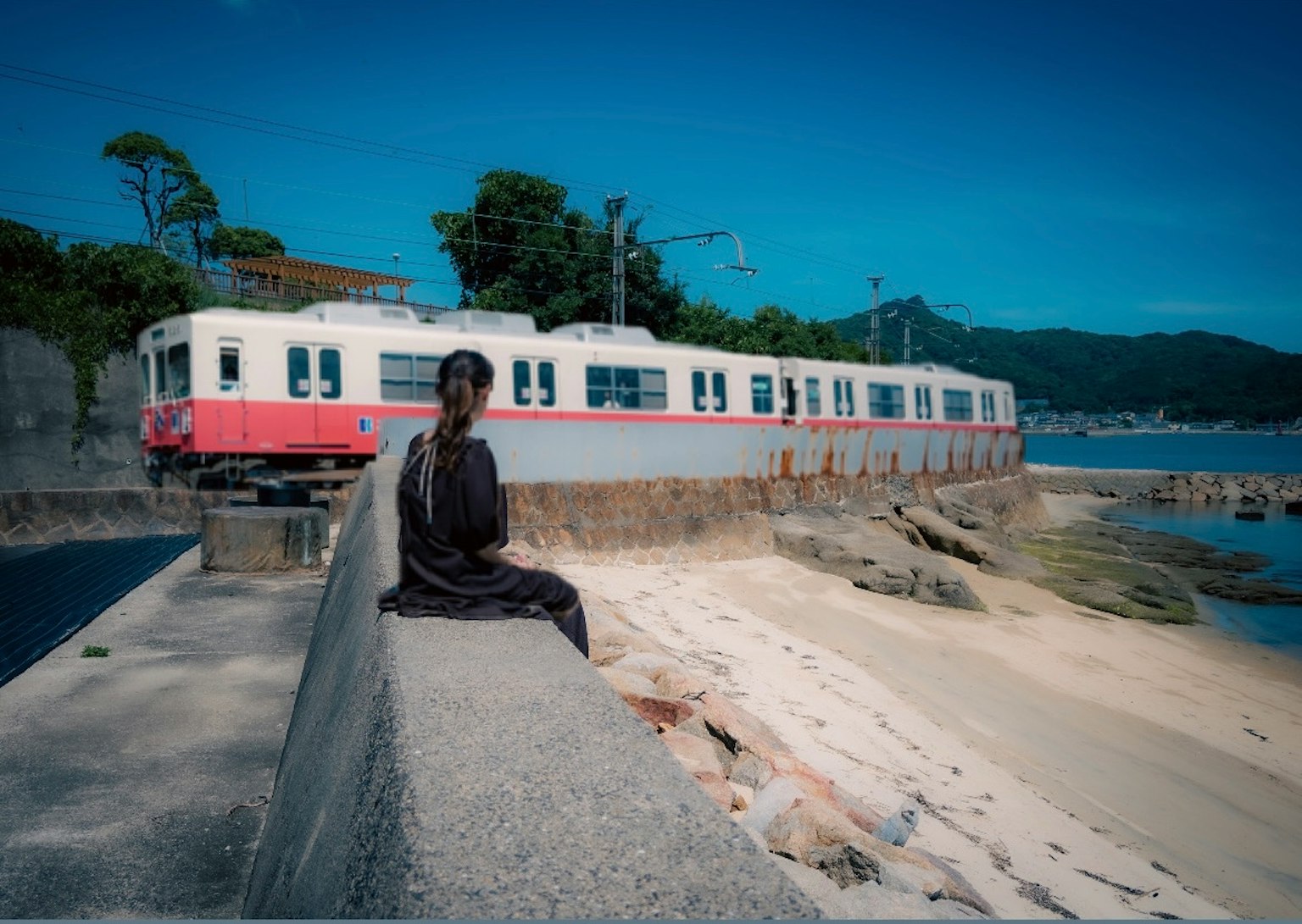 Eine Frau sitzt am Meereseisenbahngleis mit einem alten Zug