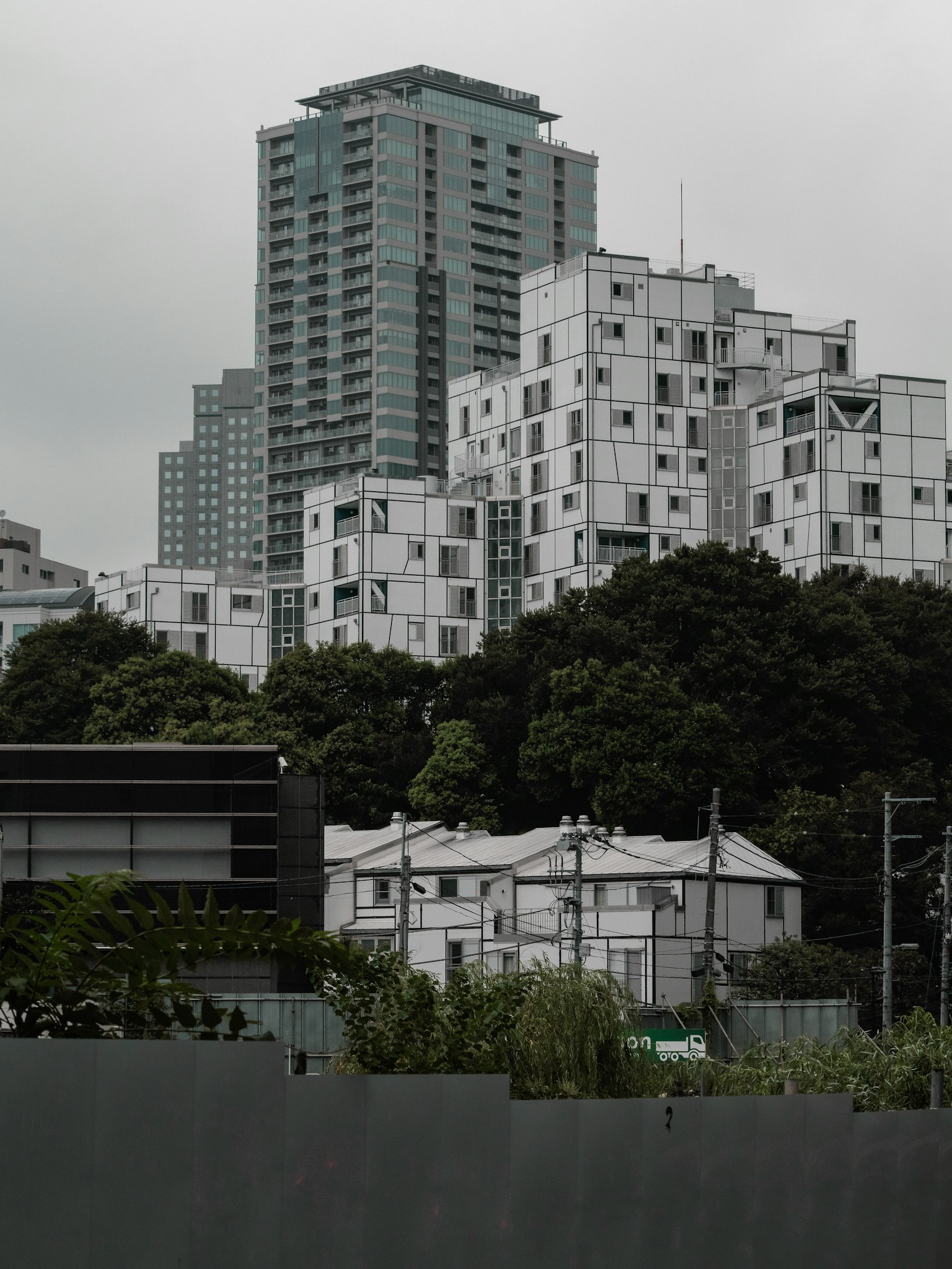 Cityscape featuring high-rise buildings and residential structures with greenery in the background