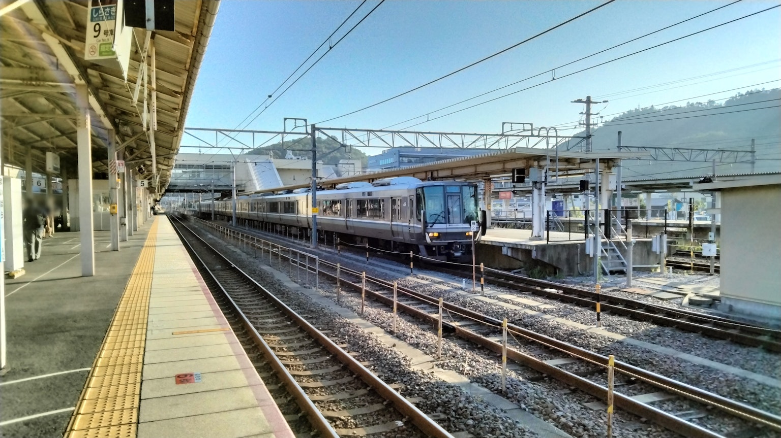 Escena tranquila de una estación de tren con un tren bajo un cielo azul claro