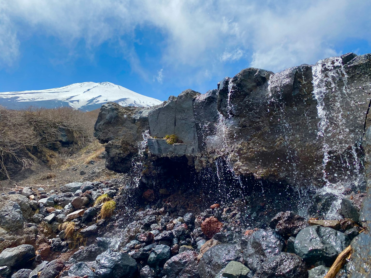 Scenic view of a snow-capped mountain with flowing water over rocks