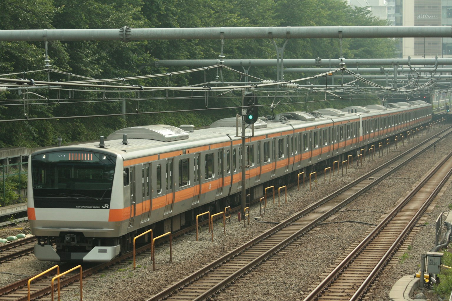 Sebuah kereta berwarna oranye dan putih melaju di rel