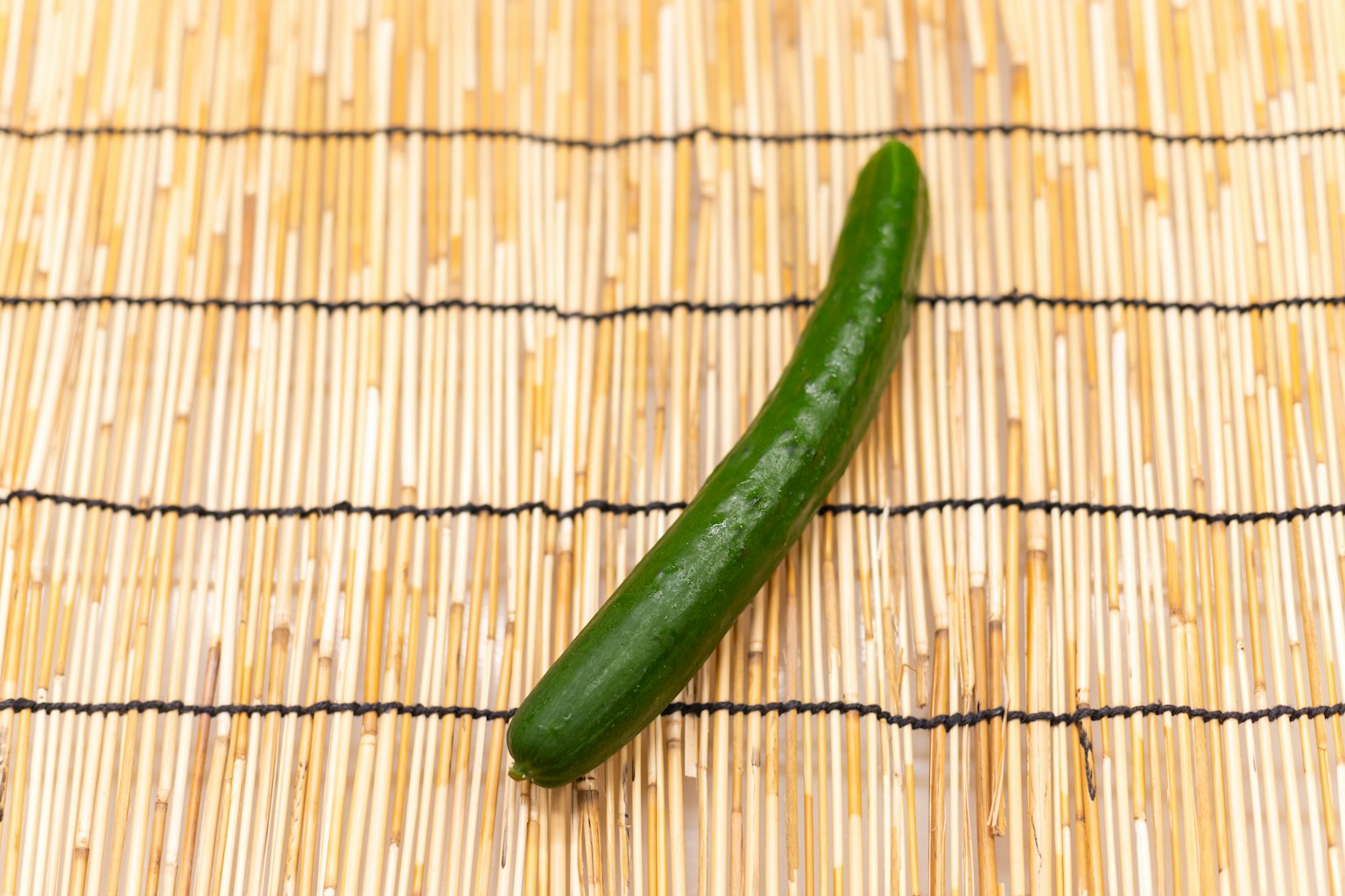 Grüne Gurke auf einem Bambusmatte platziert