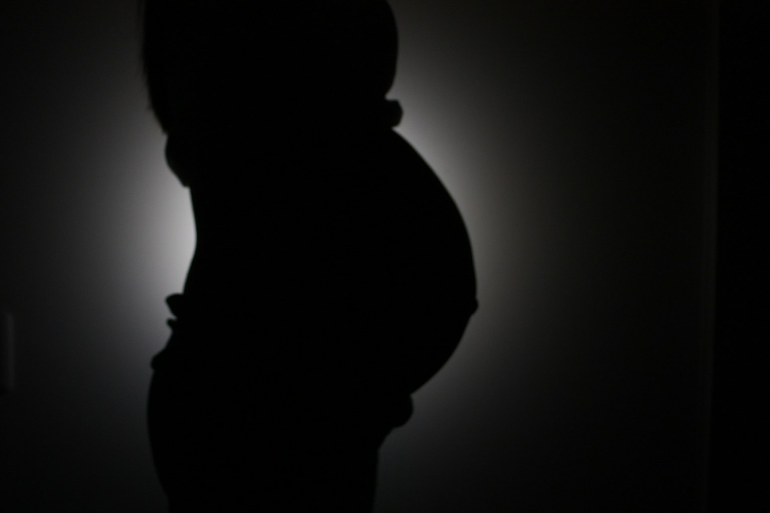Silueta de una mujer embarazada iluminada por luz de fondo