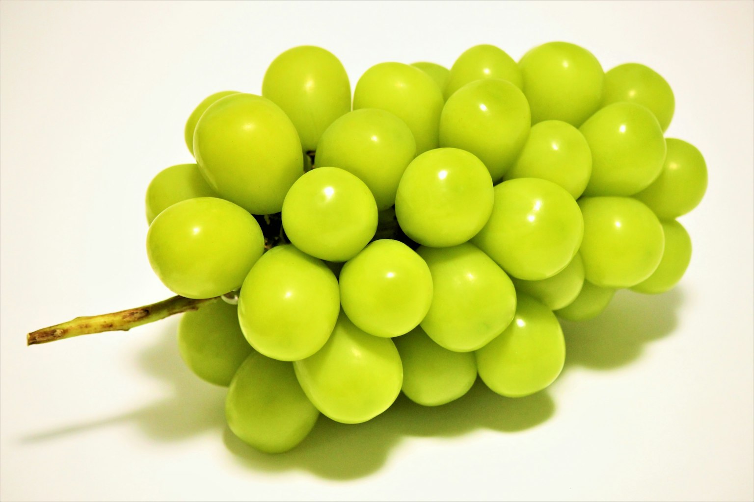 Un grappolo di uva verde vibrante su uno sfondo bianco