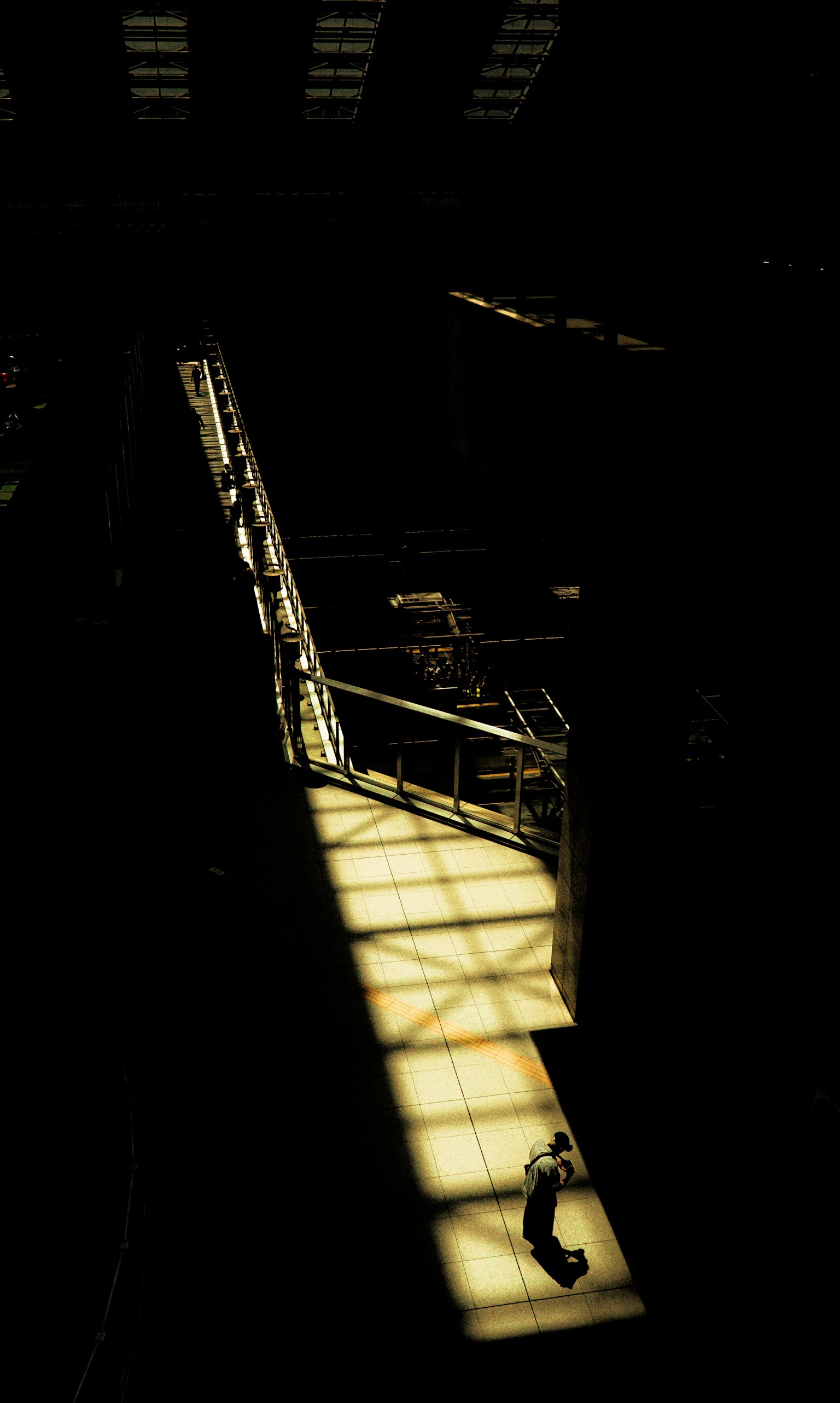 A person walking in an industrial space illuminated by bright light and shadows