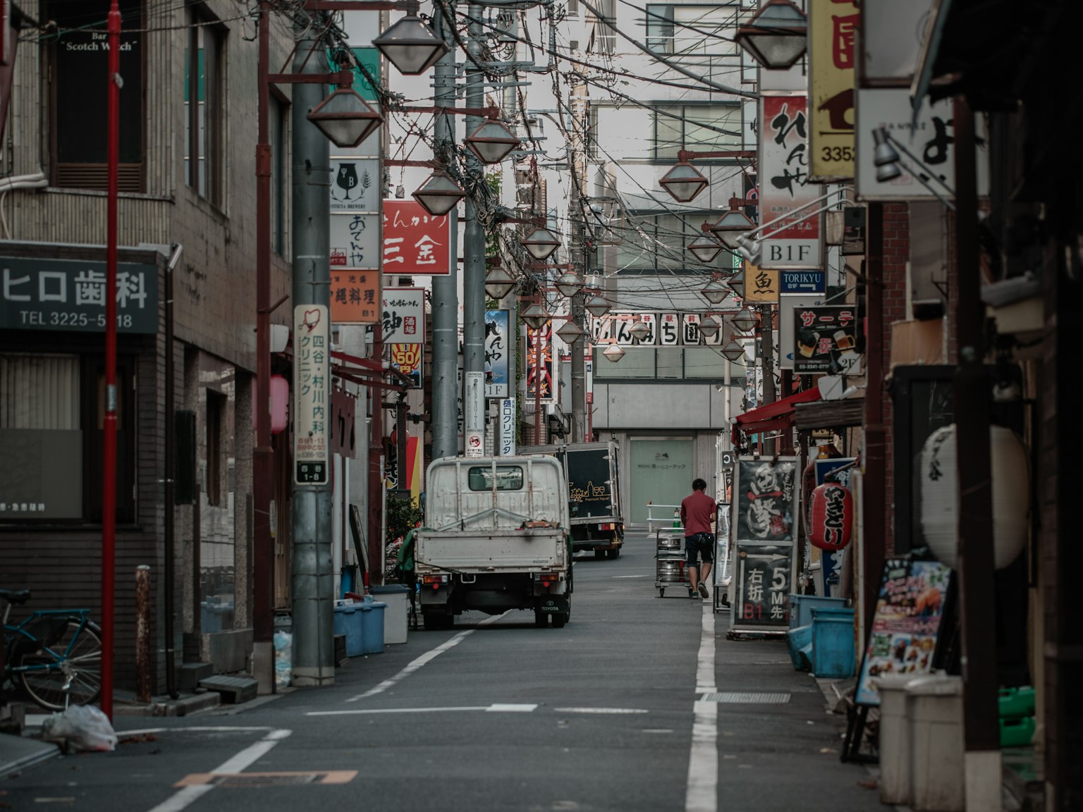 狹窄的小巷，兩旁是商店和路燈，位於日本的街區