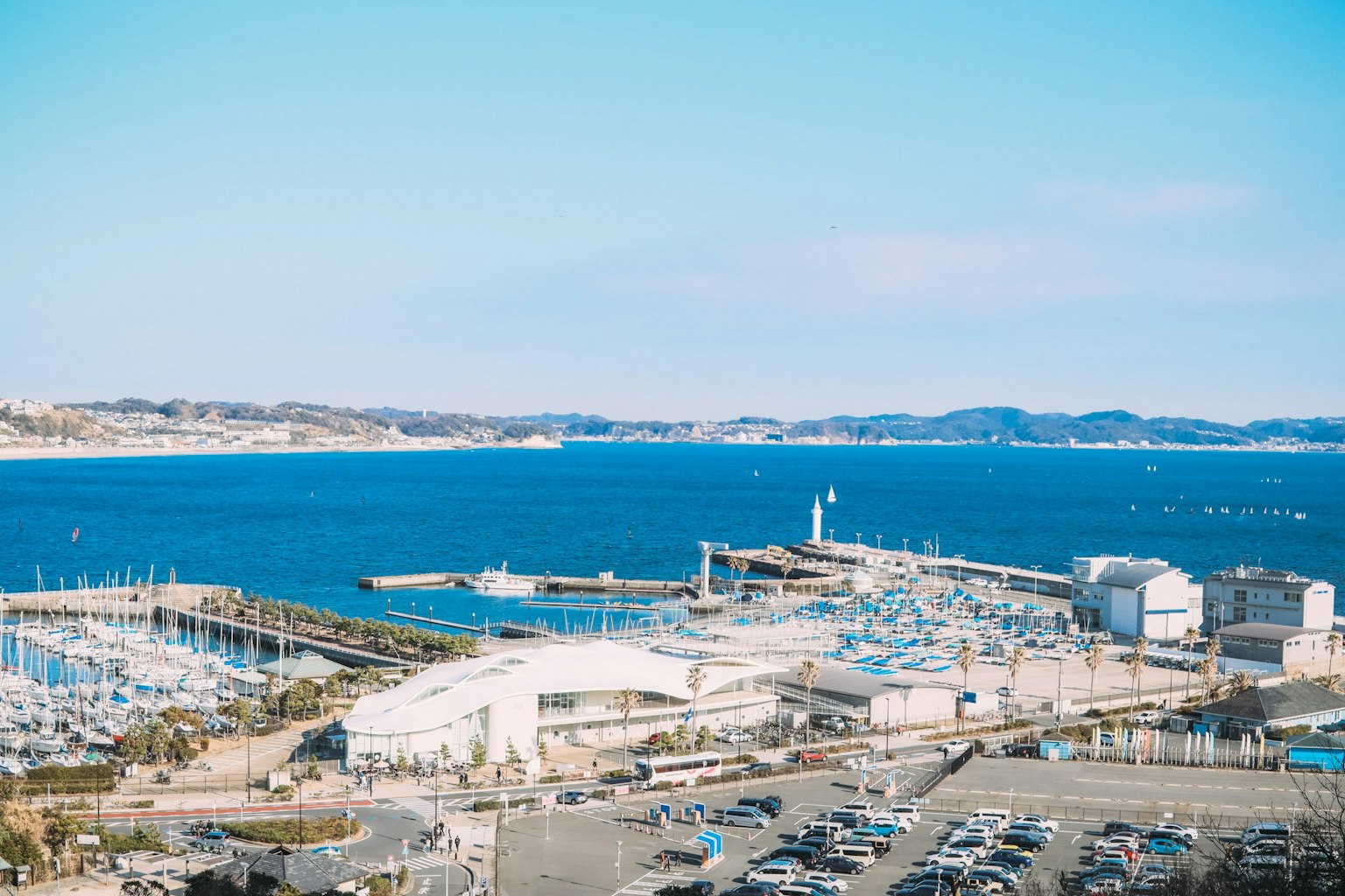 Scenic view of a blue sea and harbor Marina with boats and yachts docked Visible harbor buildings and parking lot