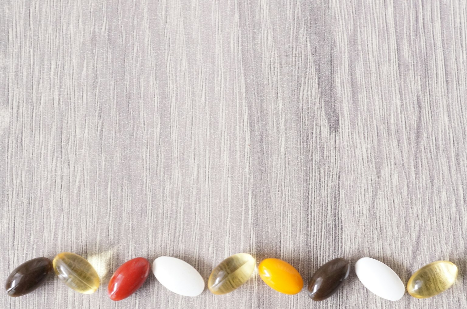 Varie capsule di integratori colorati disposte su un tavolo di legno