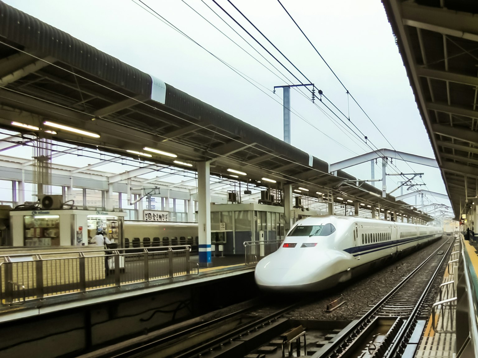 Tàu Shinkansen đến ga với đường ray và cấu trúc ga nhìn thấy rõ ràng