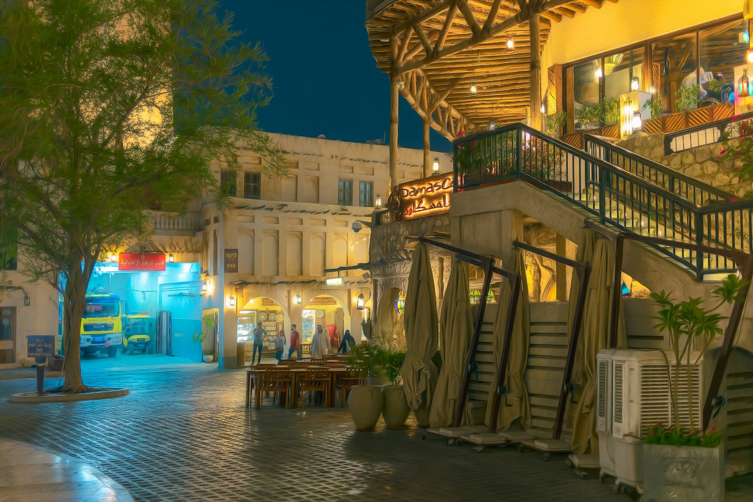 ภาพกลางคืนของร้านกาแฟที่มีบันไดและโต๊ะข้างนอก