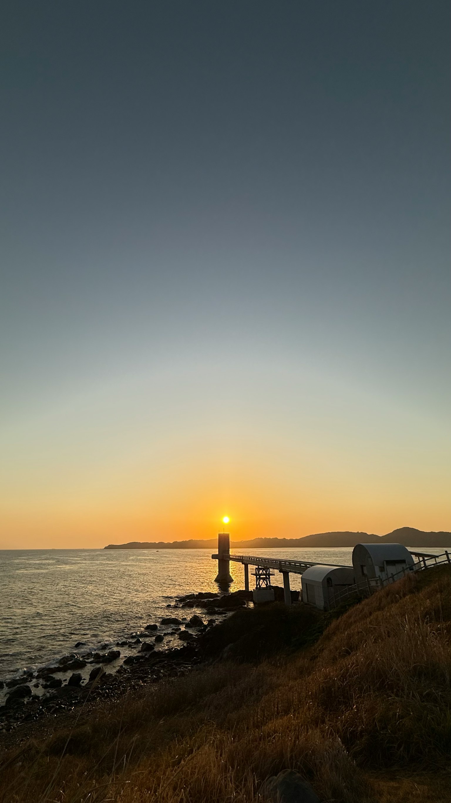 Schöner Sonnenuntergang über der Küste mit einem sichtbaren Pier