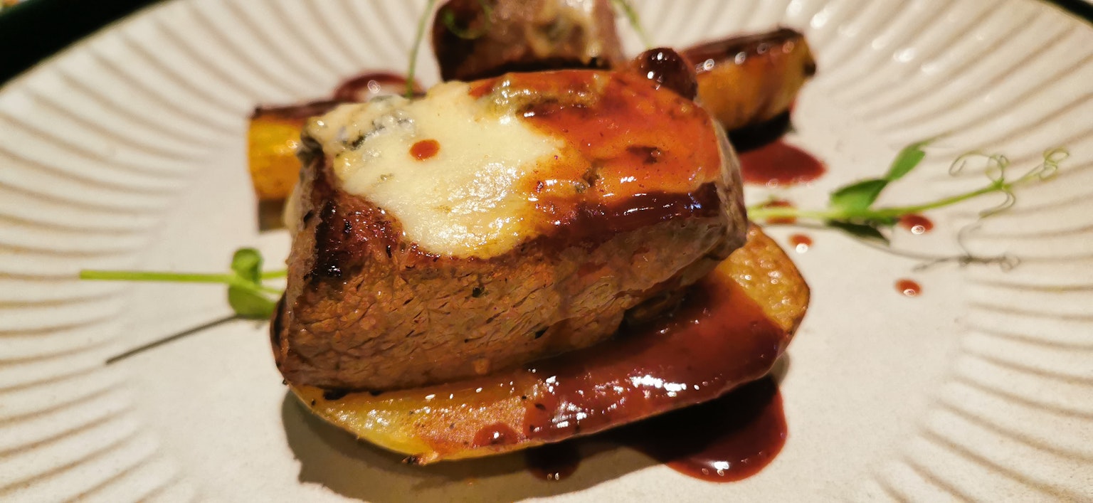 Un delicioso plato de carne presentado con salsa y guarniciones