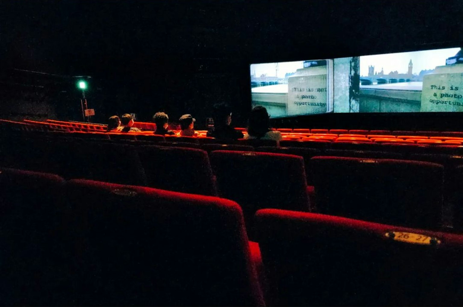 Dunkles Kino mit roten Sitzen und sichtbaren Bildschirmen