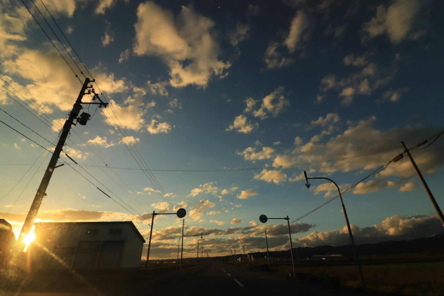 Cielo de atardecer pintoresco con postes de luz en silueta