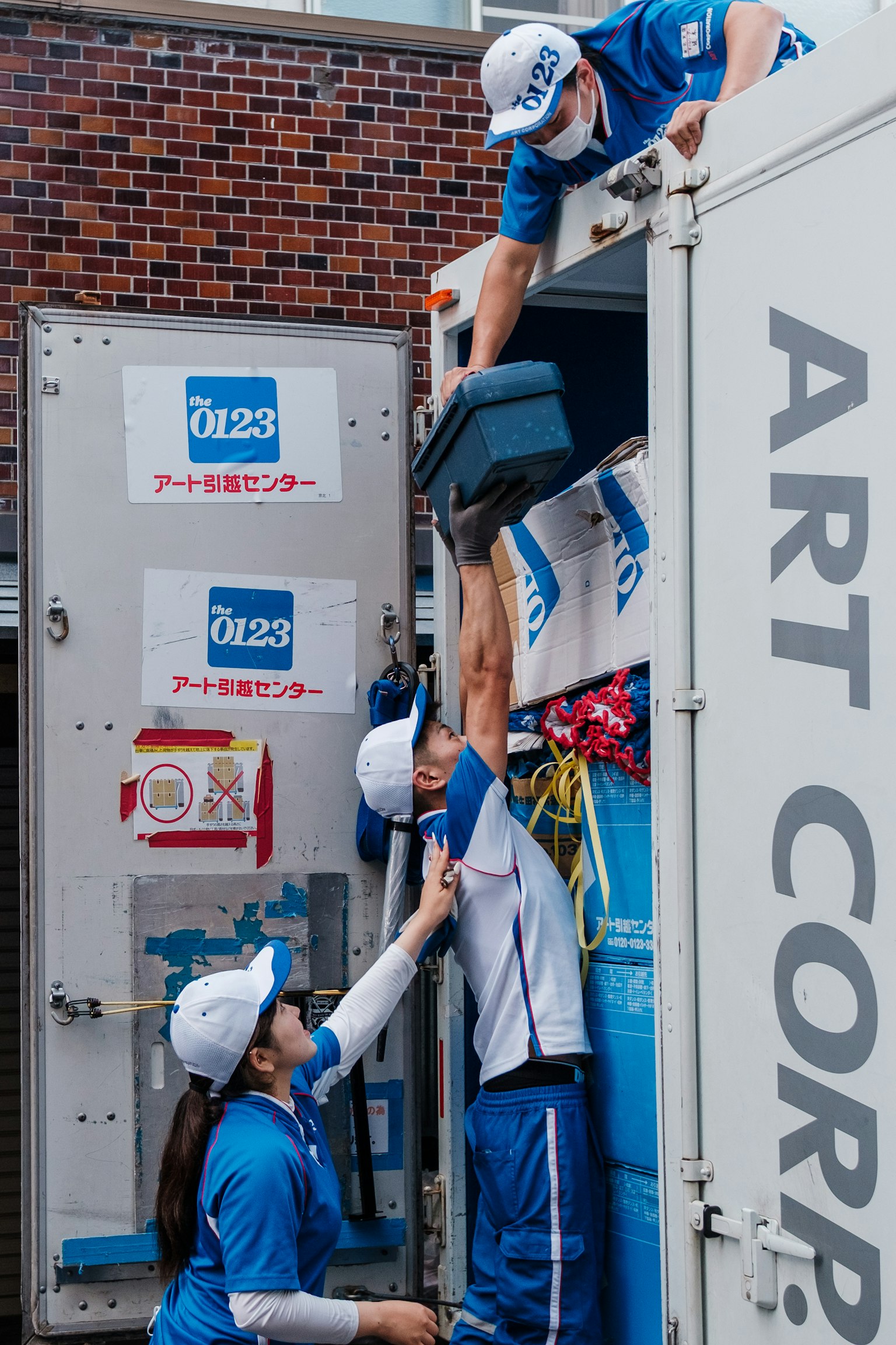 作業服を着た男性と女性がトラックから荷物を運び出している様子