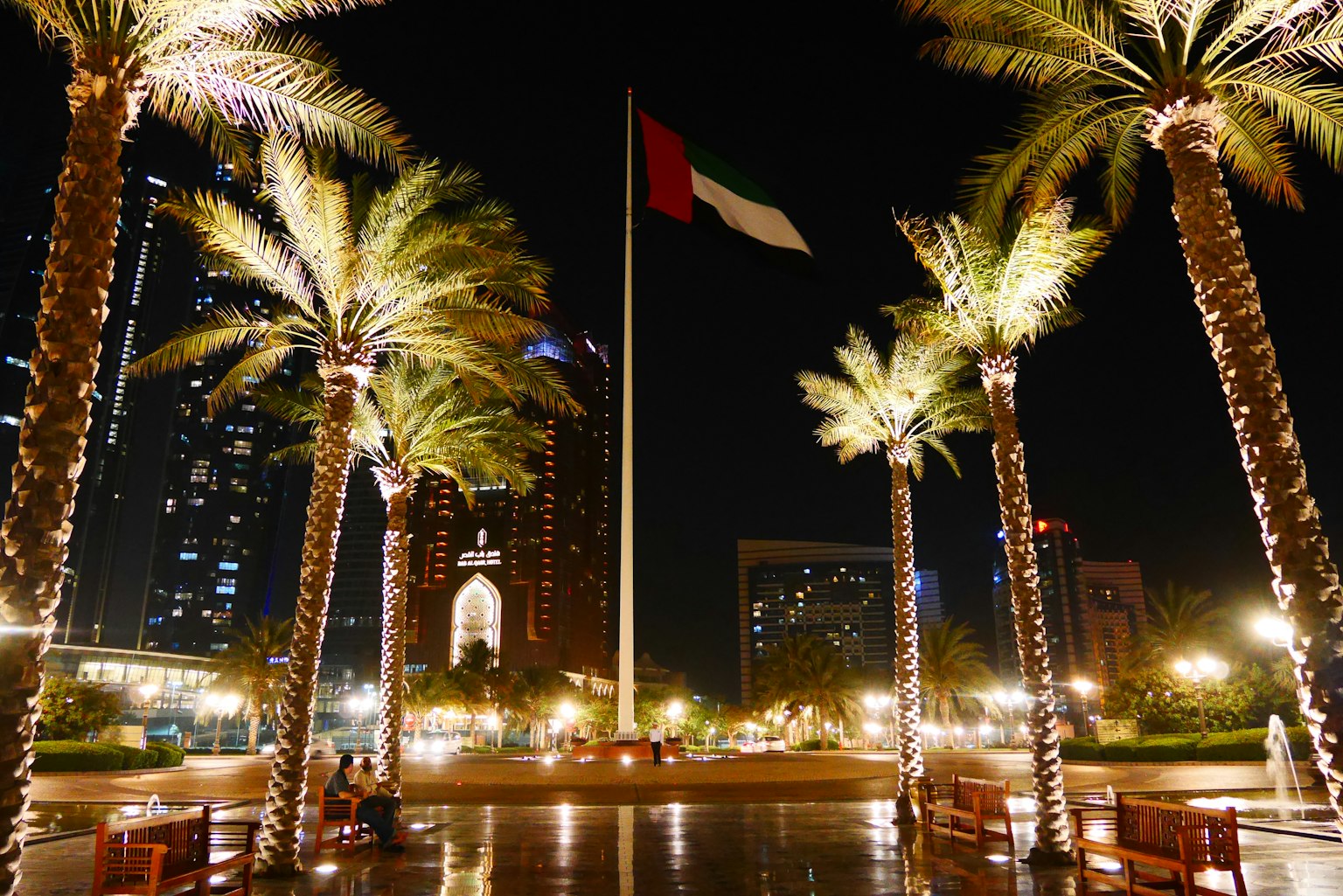 Indonesian flag waving at night surrounded by palm trees and city lights