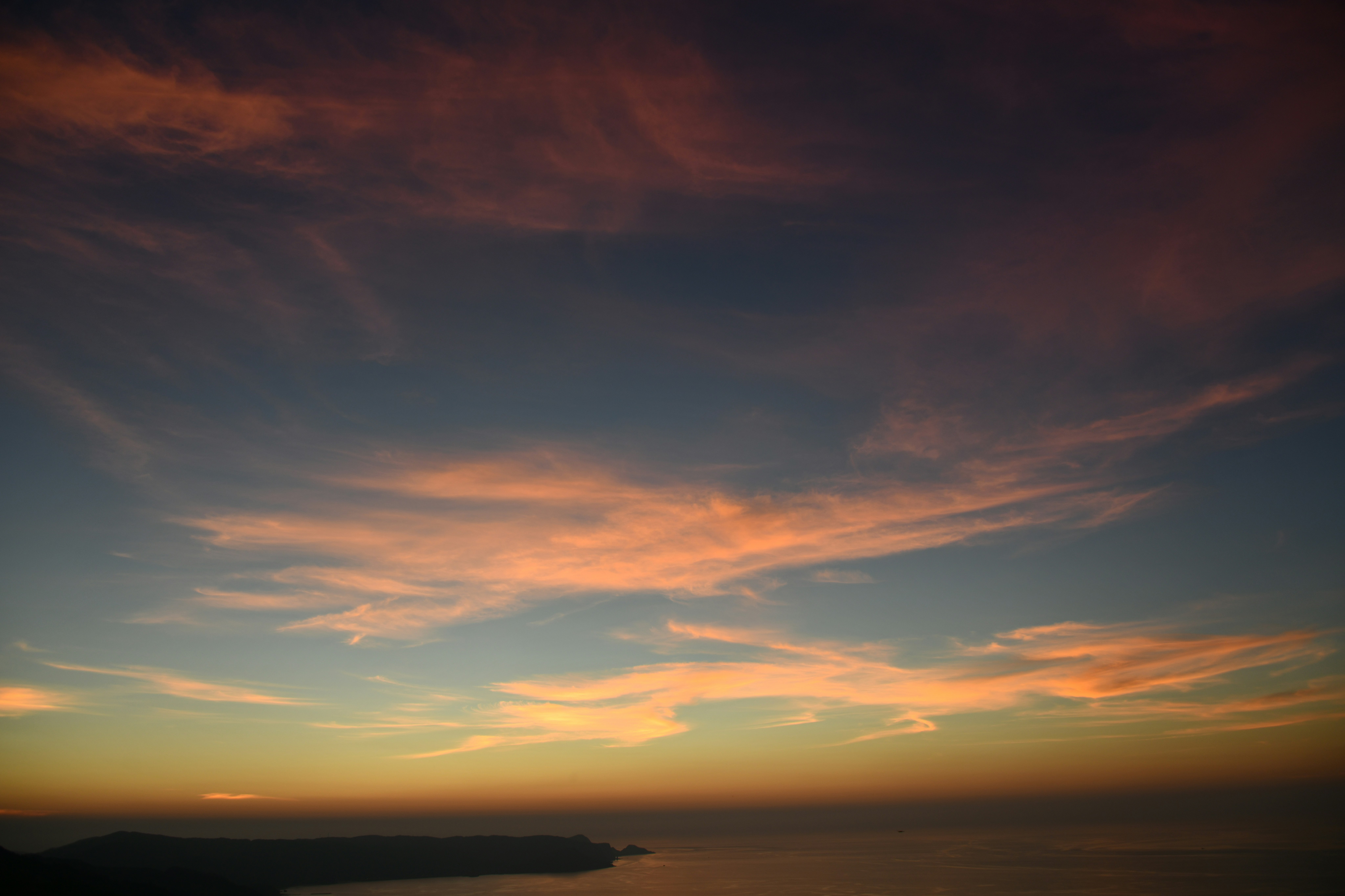 夕暮れの海辺に広がる雲とオレンジ色の空