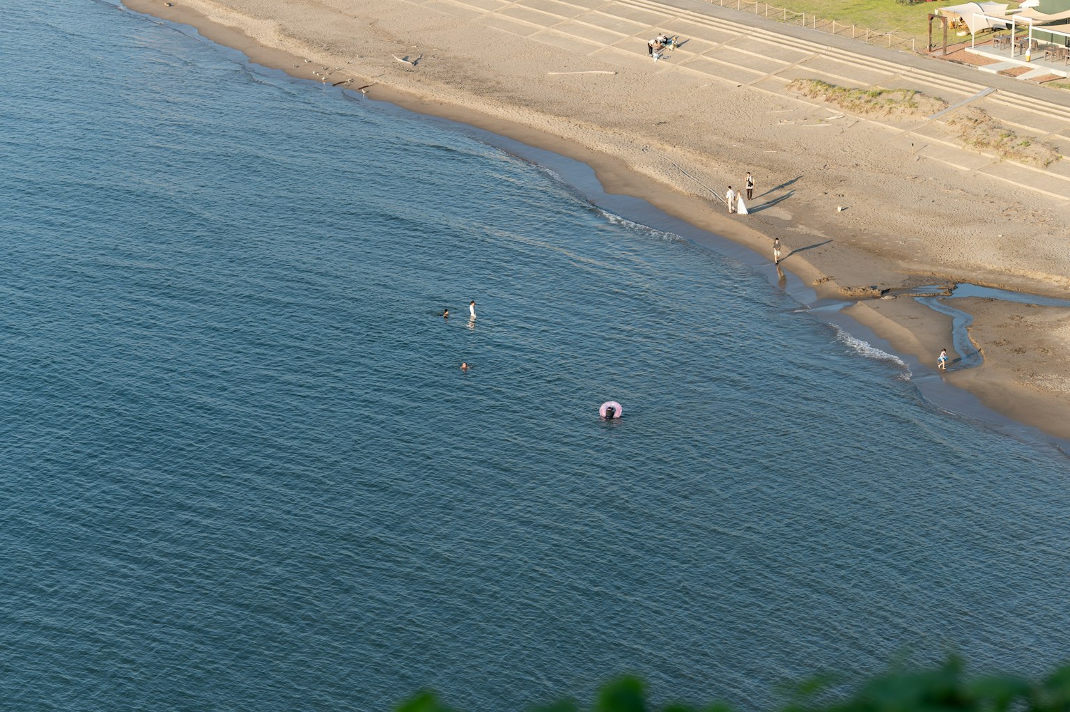 Küstenansicht mit Sandstrand und sichtbaren Menschen Bunte Sonnenschirme auf der Wasseroberfläche