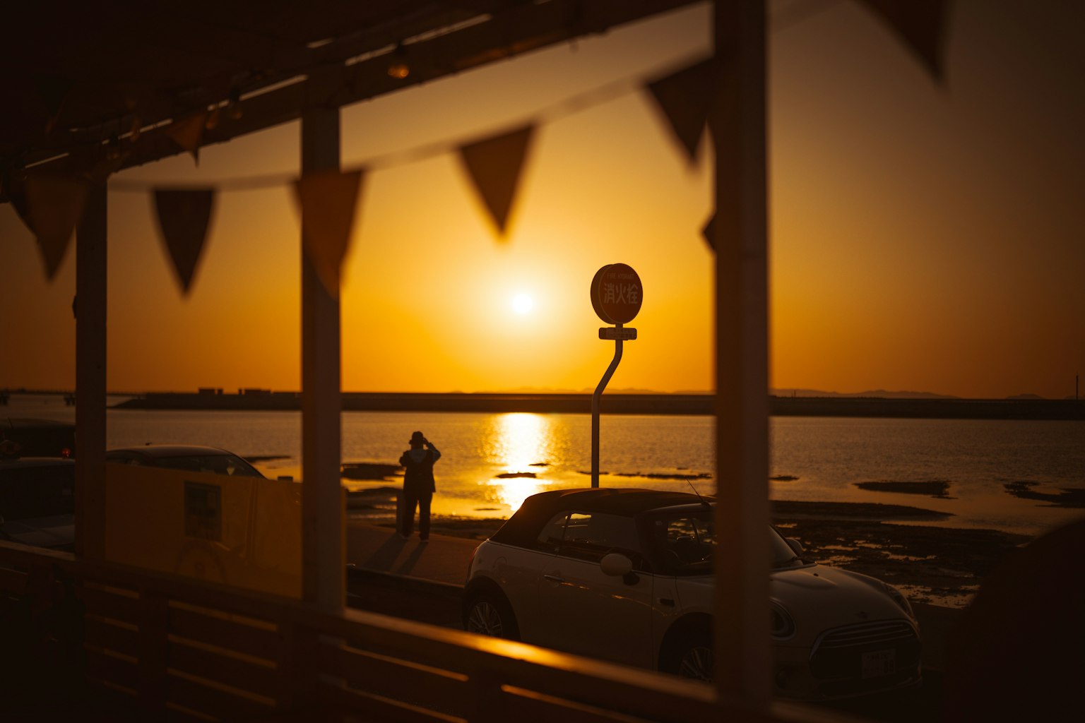 Silhouette di una persona sulla spiaggia al tramonto con bandierine colorate in primo piano