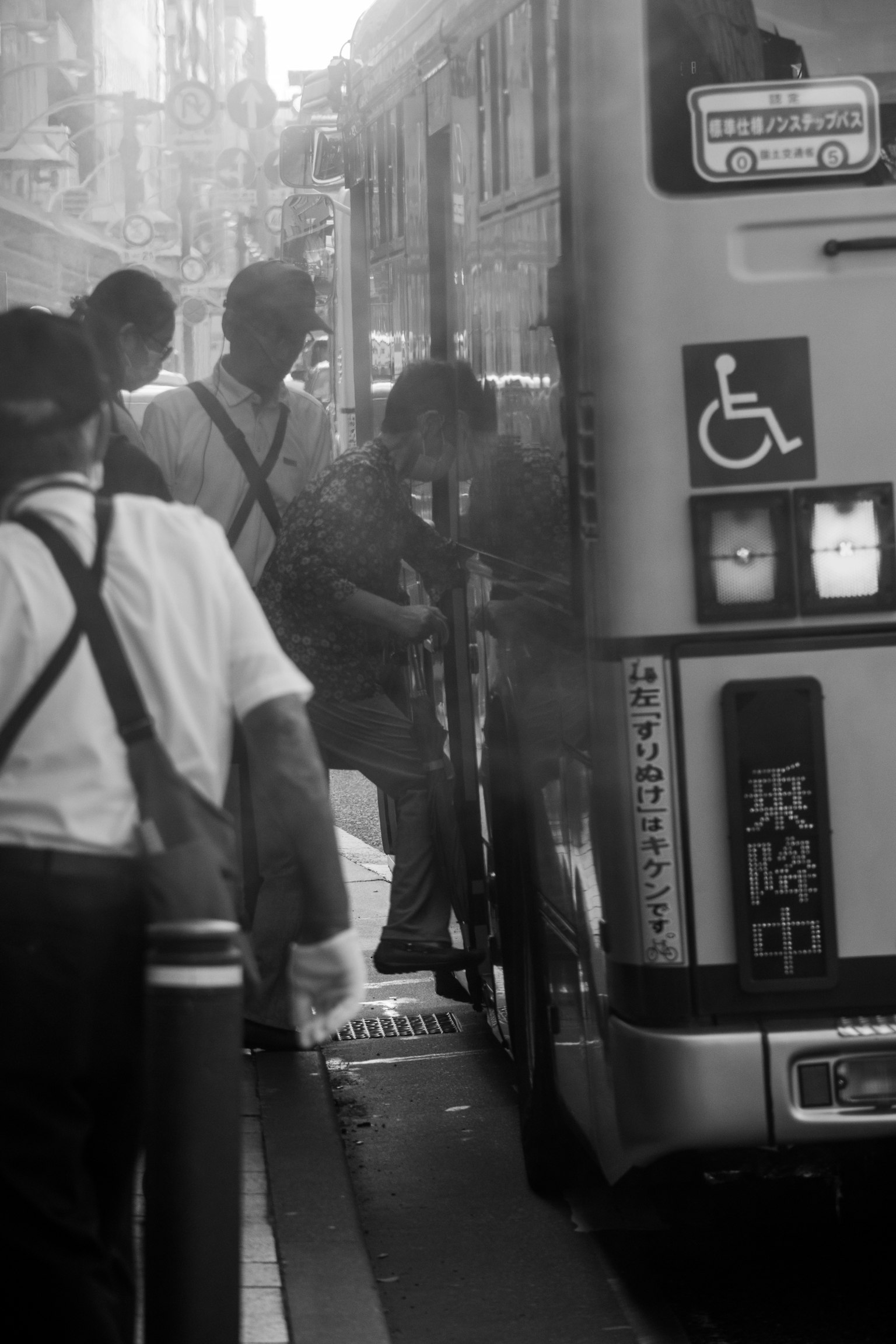 Foto in bianco e nero di persone che salgono su un autobus con un simbolo di accessibilità visibile