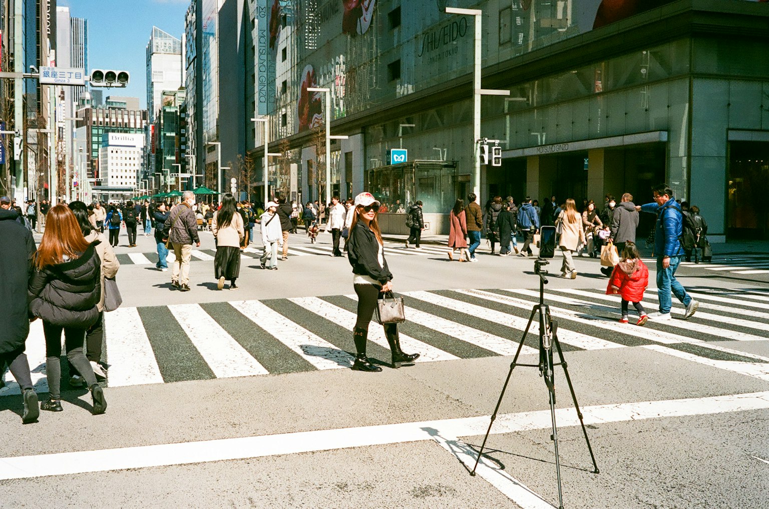 ทางม้าลายที่แออัดมีผู้หญิงยืนอยู่และคนเดินเท้าหลายคน