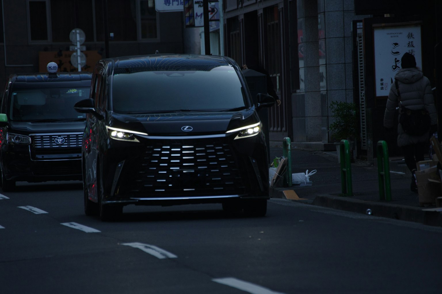 Un vehículo negro conduciendo por una calle poco iluminada