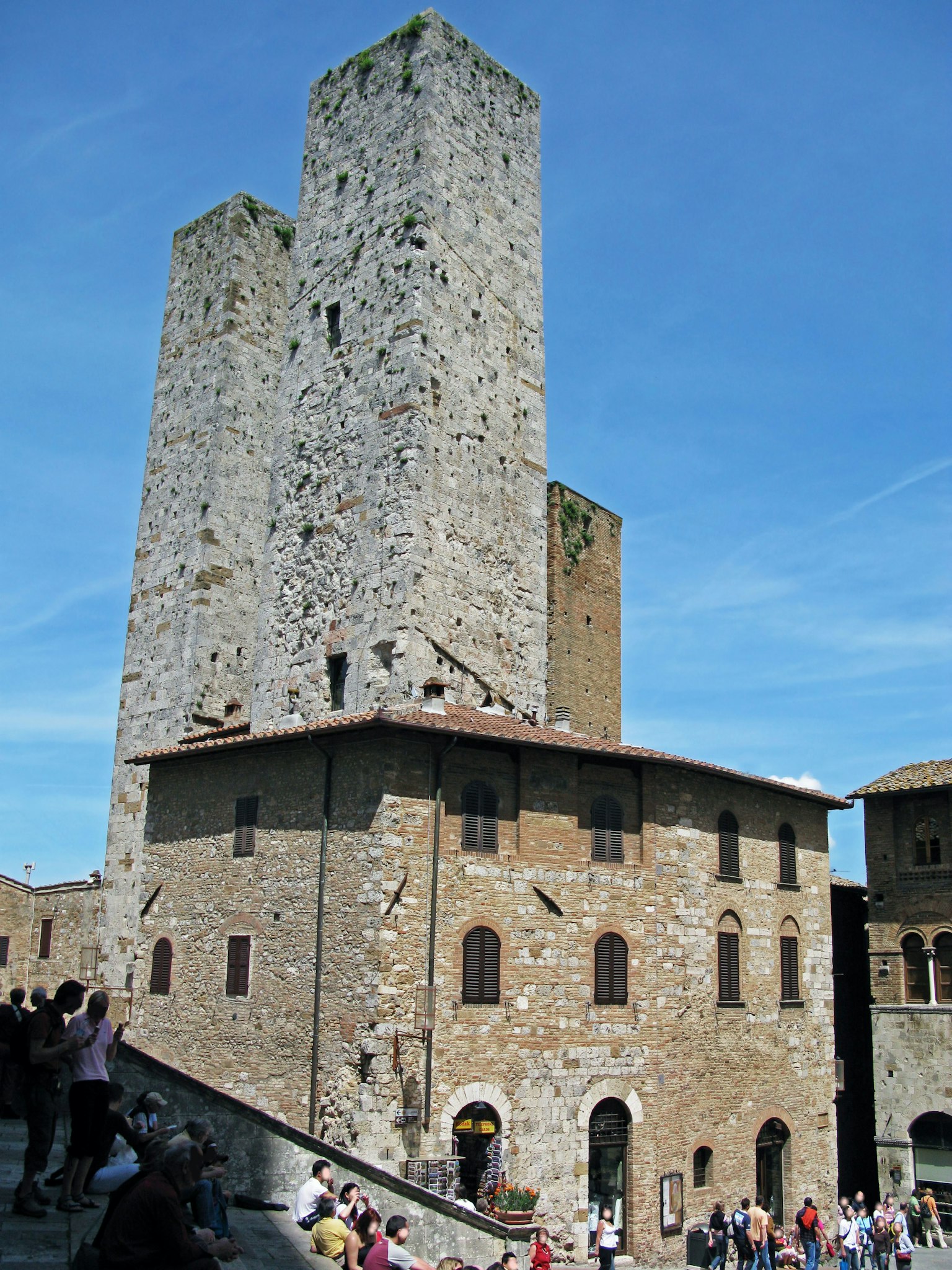 Landscape featuring medieval towers and stone buildings with many tourists in San Gimignano
