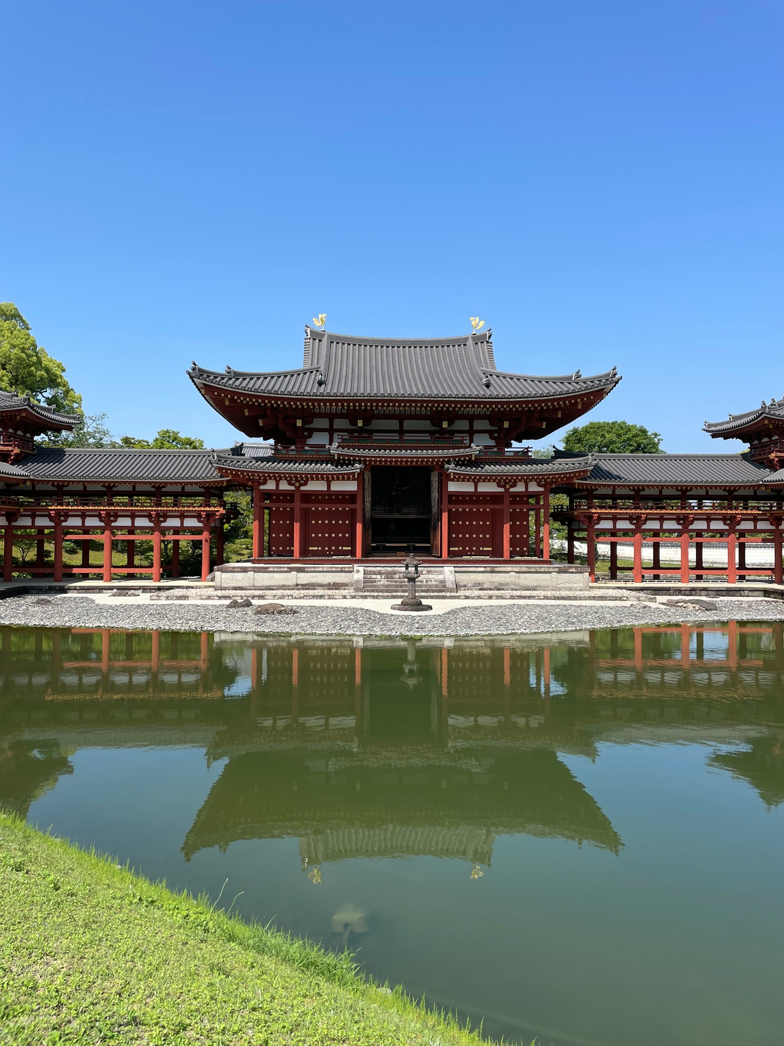 傳統日本建築位於寧靜的池塘前，映出清澈的藍天