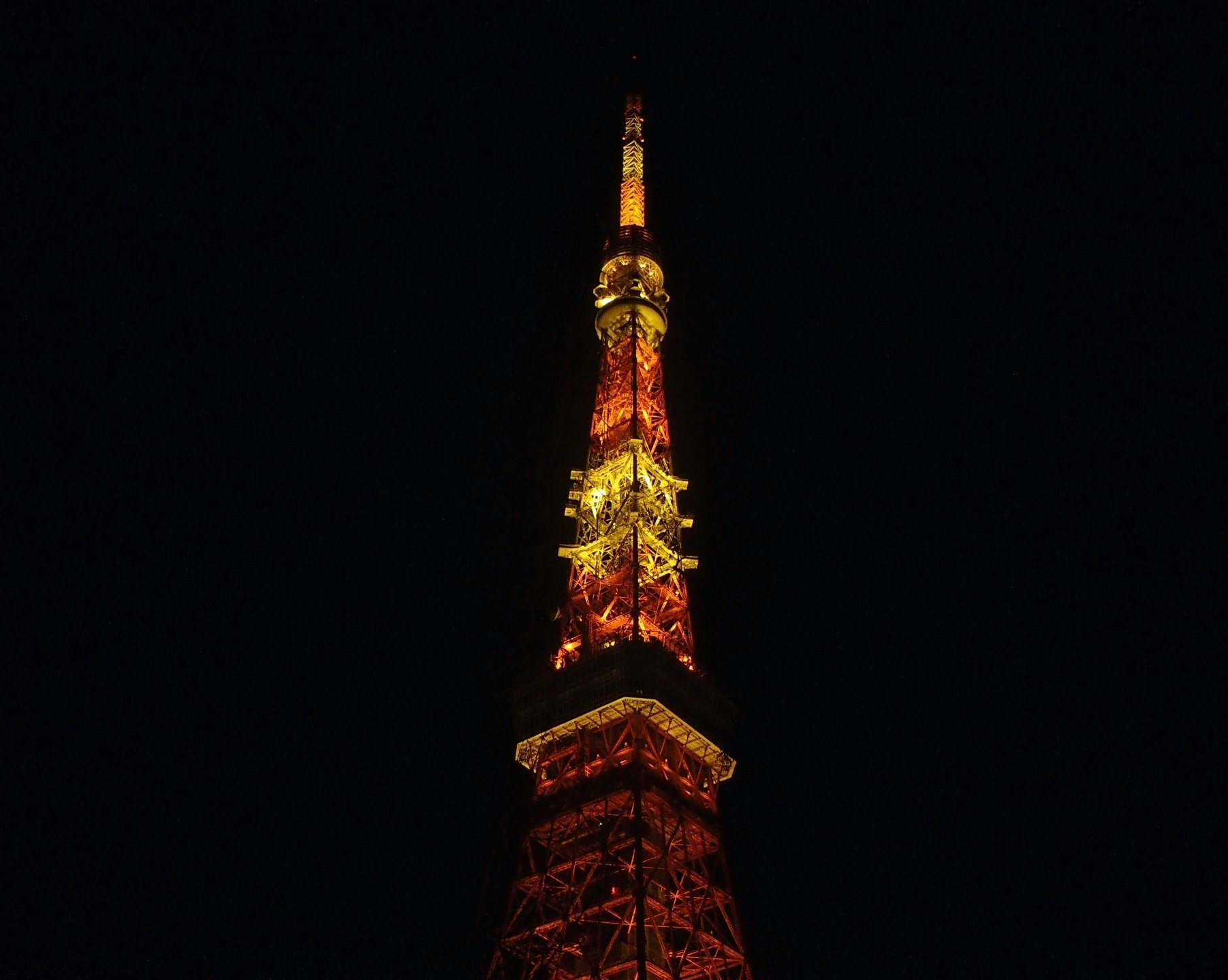 夜空にそびえるライトアップされたエッフェル塔の上部