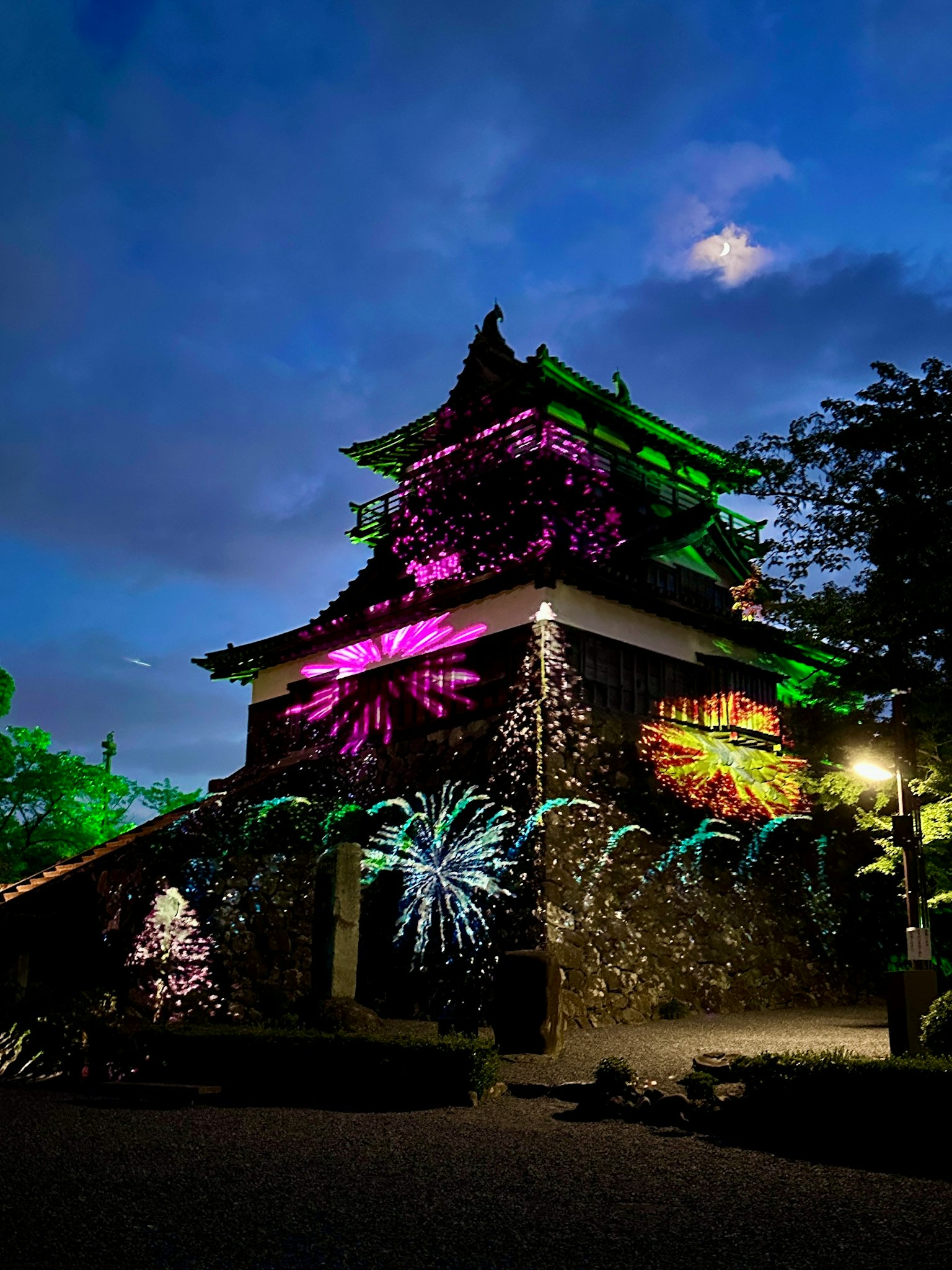 Historische Burg mit bunten Lichtern bei Nacht beleuchtet