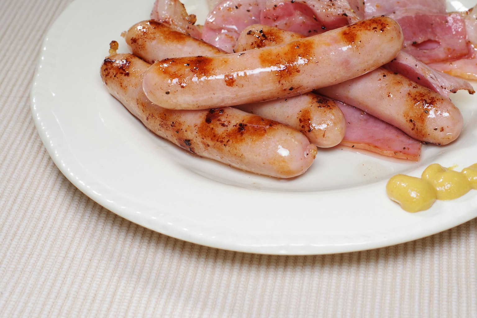 Un piatto di salsicce grigliate e fette di prosciutto