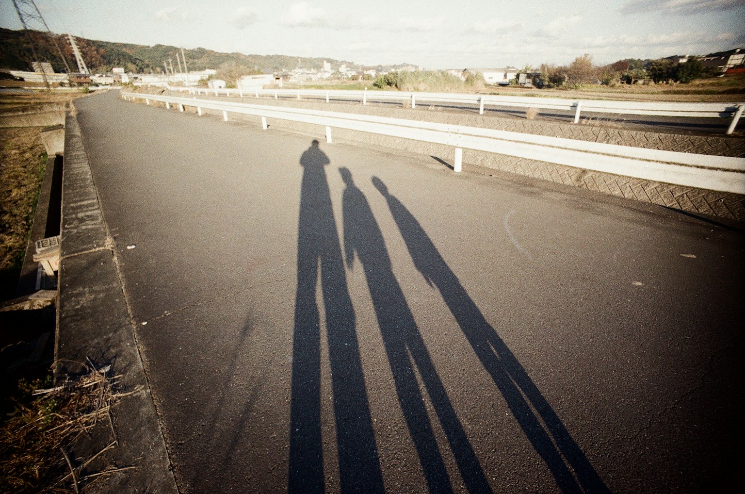 Long shadows of a family silhouette cast on the road