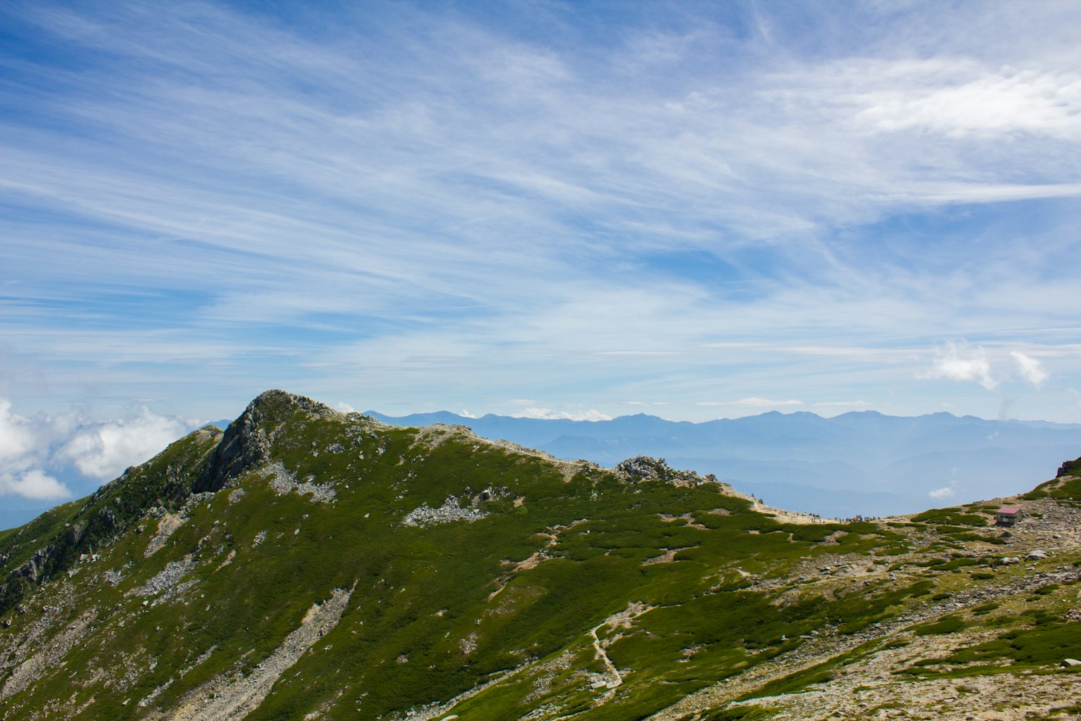 Vista escénica de montañas verdes bajo un cielo azul con nubes