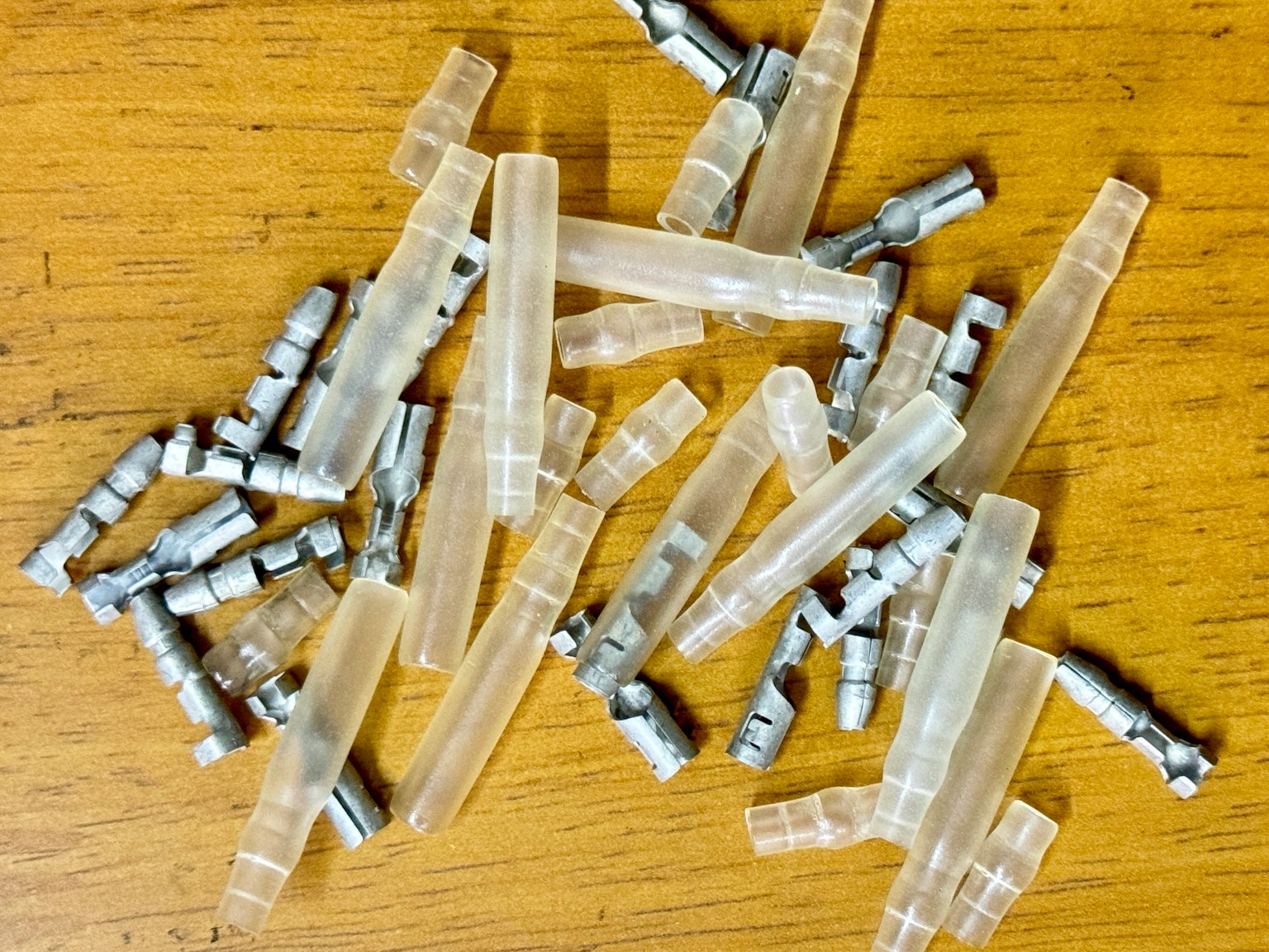 Eine Ansammlung transparenter Stecker und Metallteile, die auf einer Holzoberfläche verstreut sind