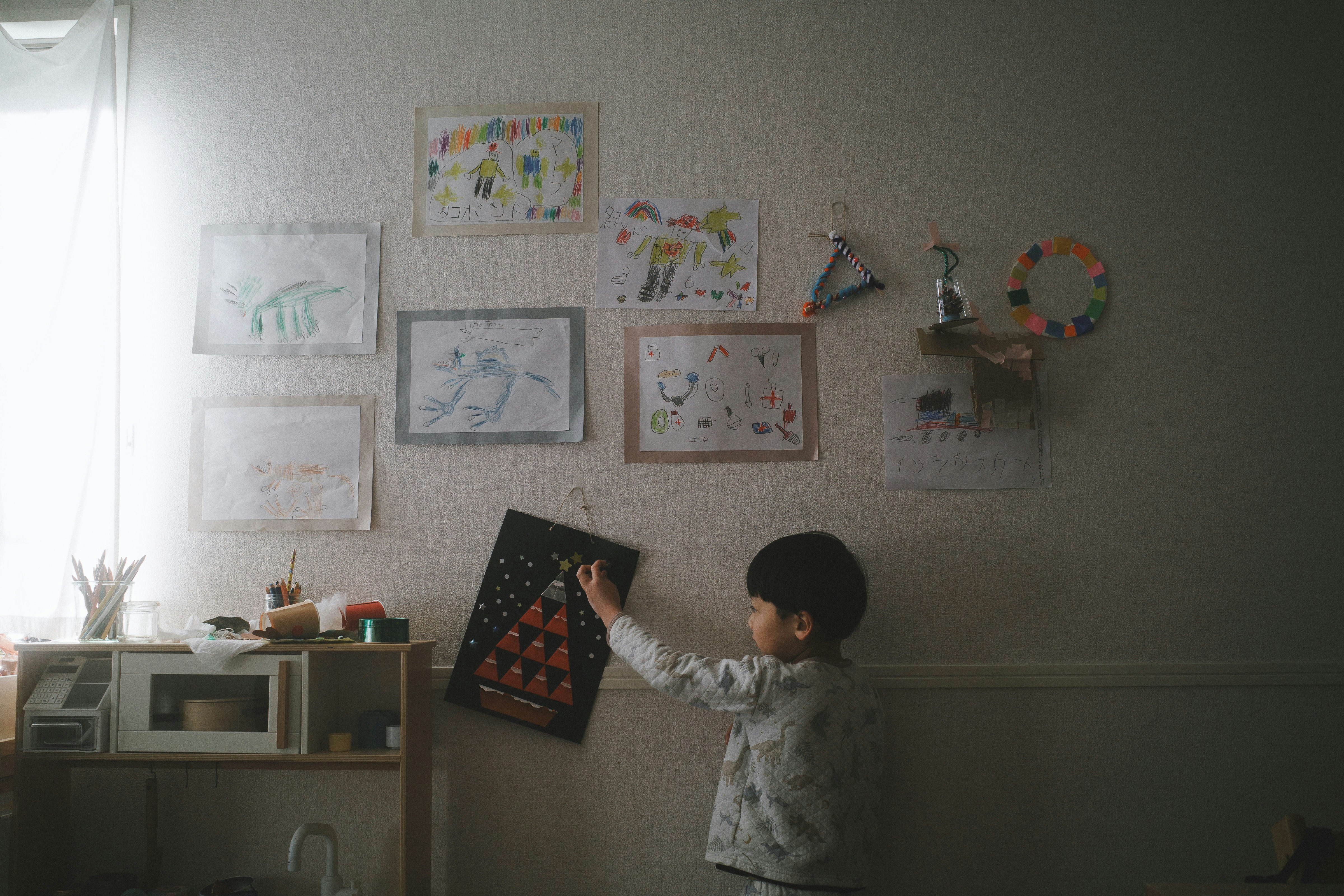 壁に貼られた絵の前で遊ぶ子ども