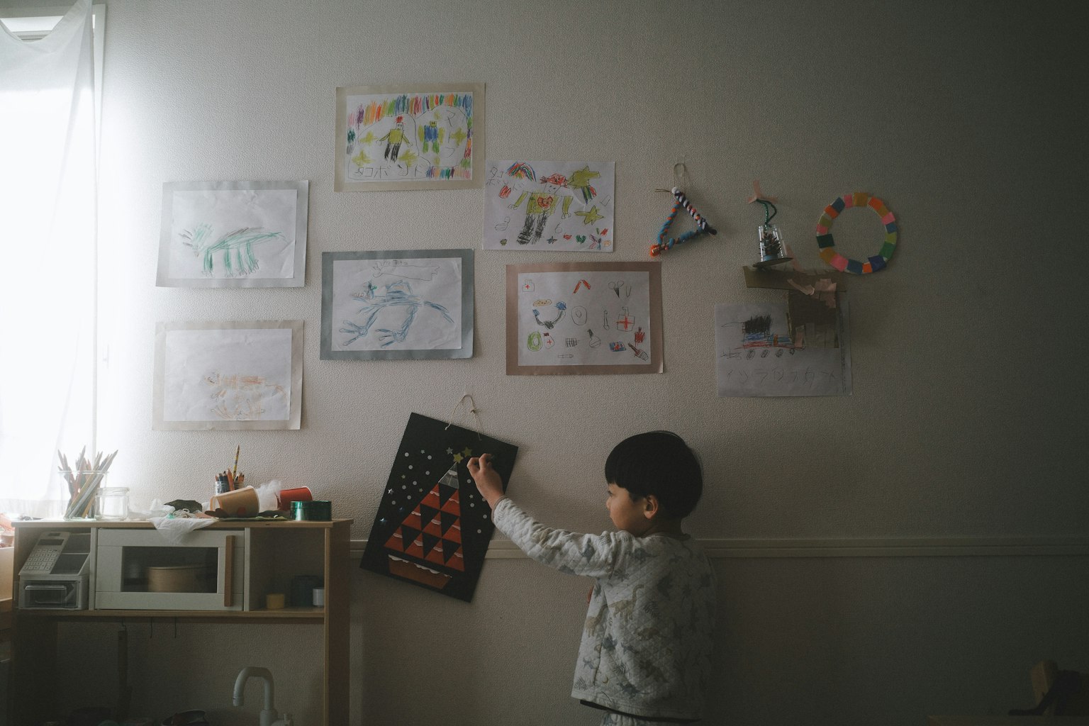 A child observing drawings on a wall in a cozy room
