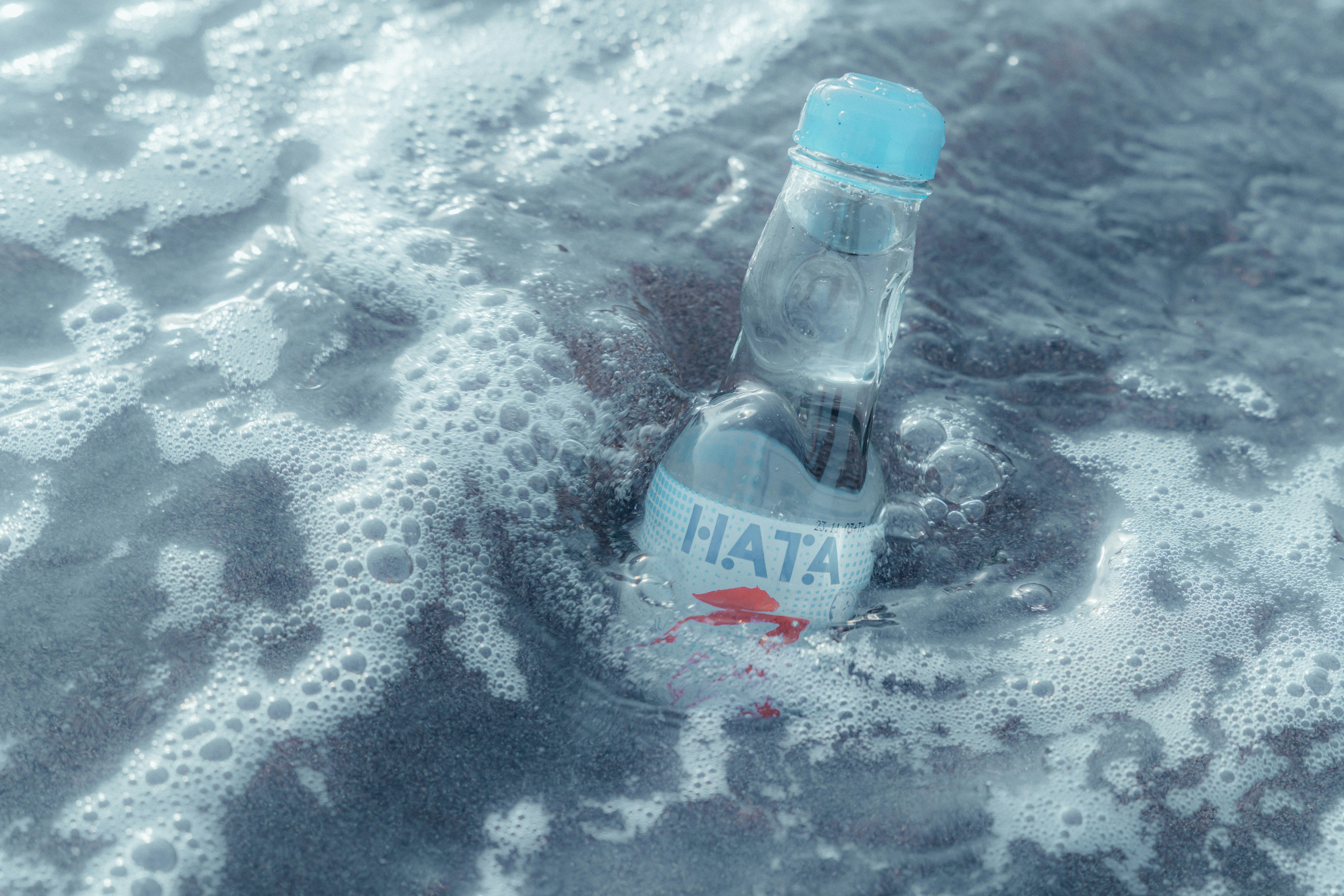 botol ramune mengapung di atas air berbusa