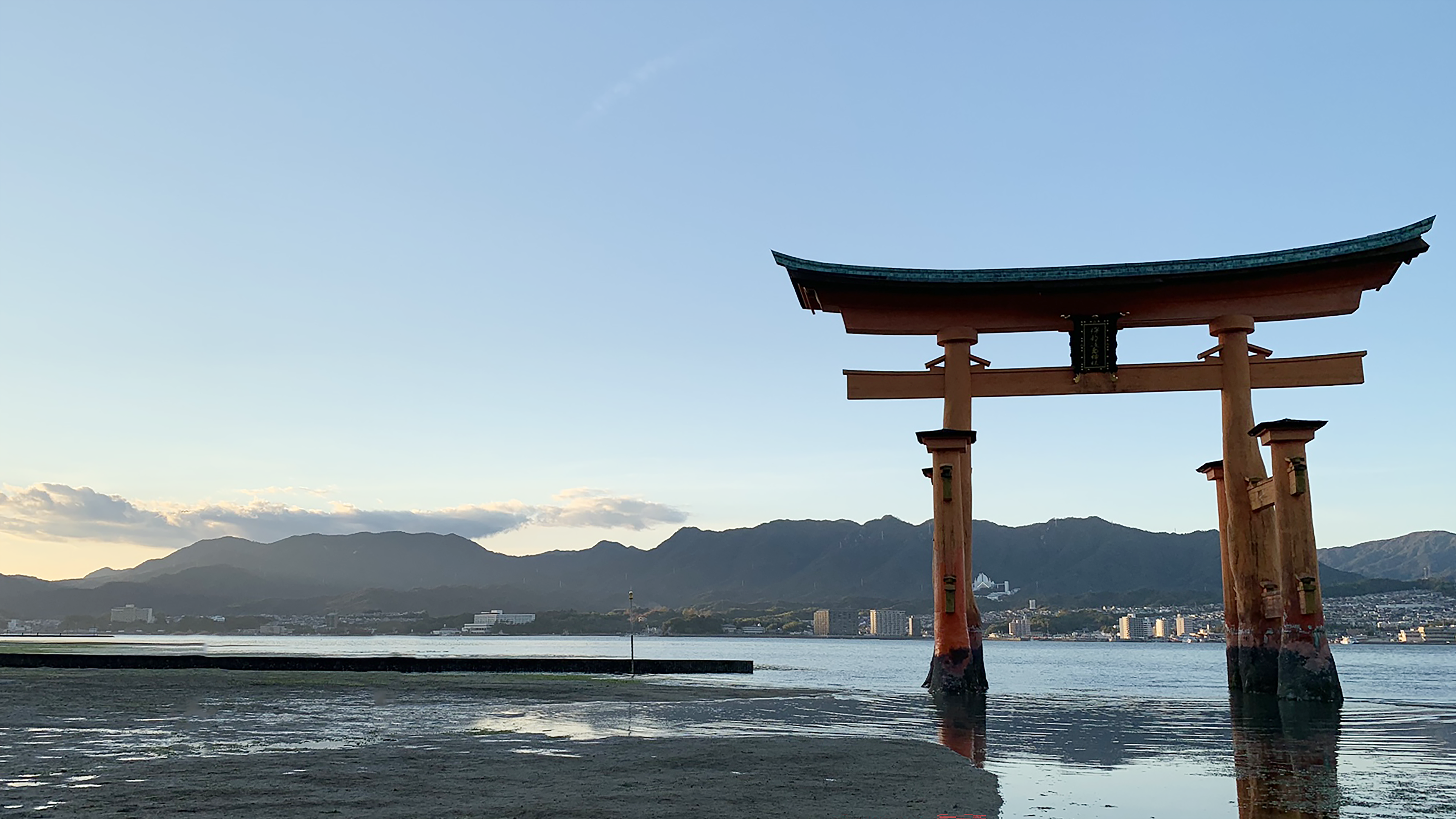 海辺の鳥居と遠景の山並みが広がる風景